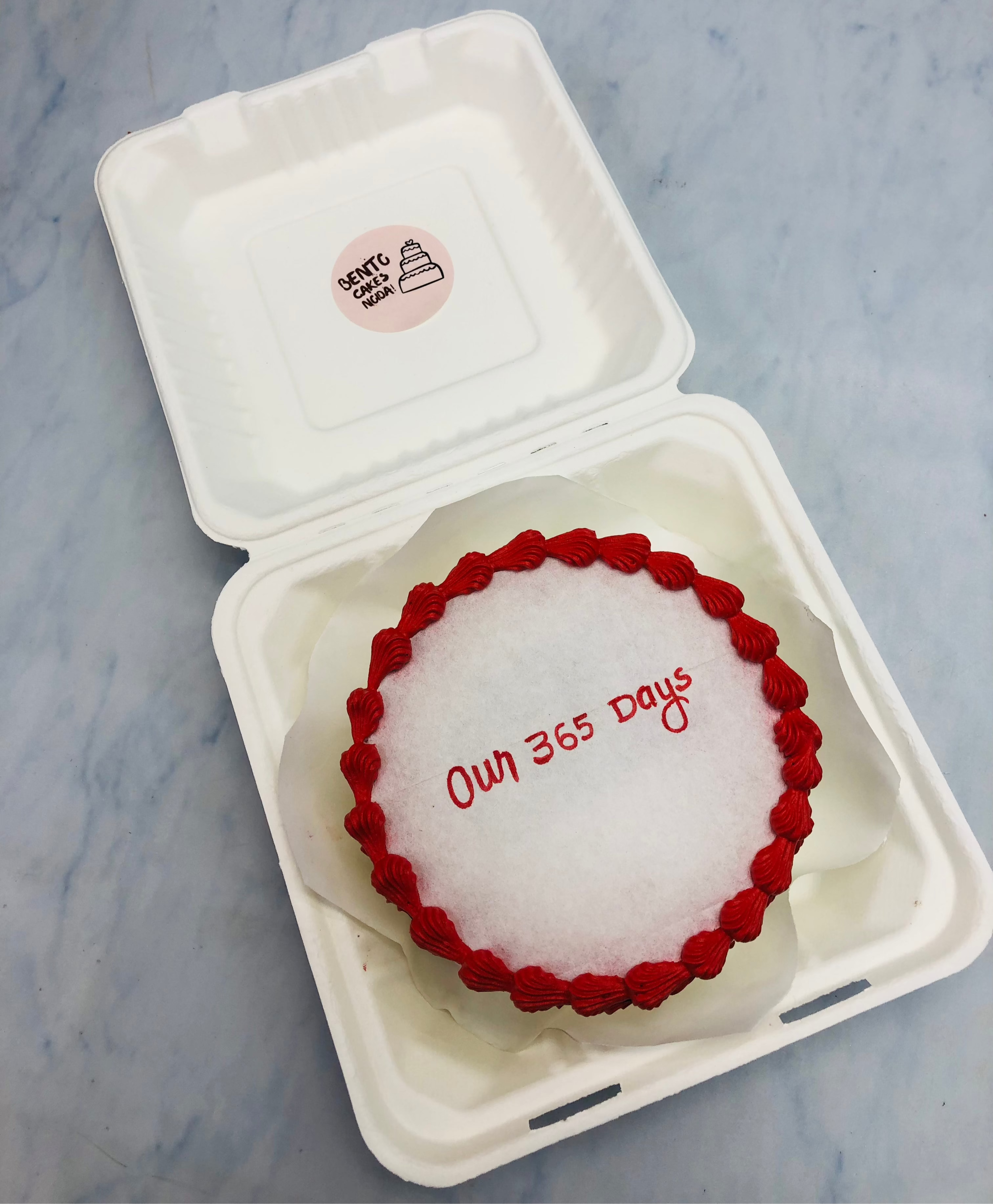 A basic 1st anniversary theme fire bento cake having red truffle design on its border.