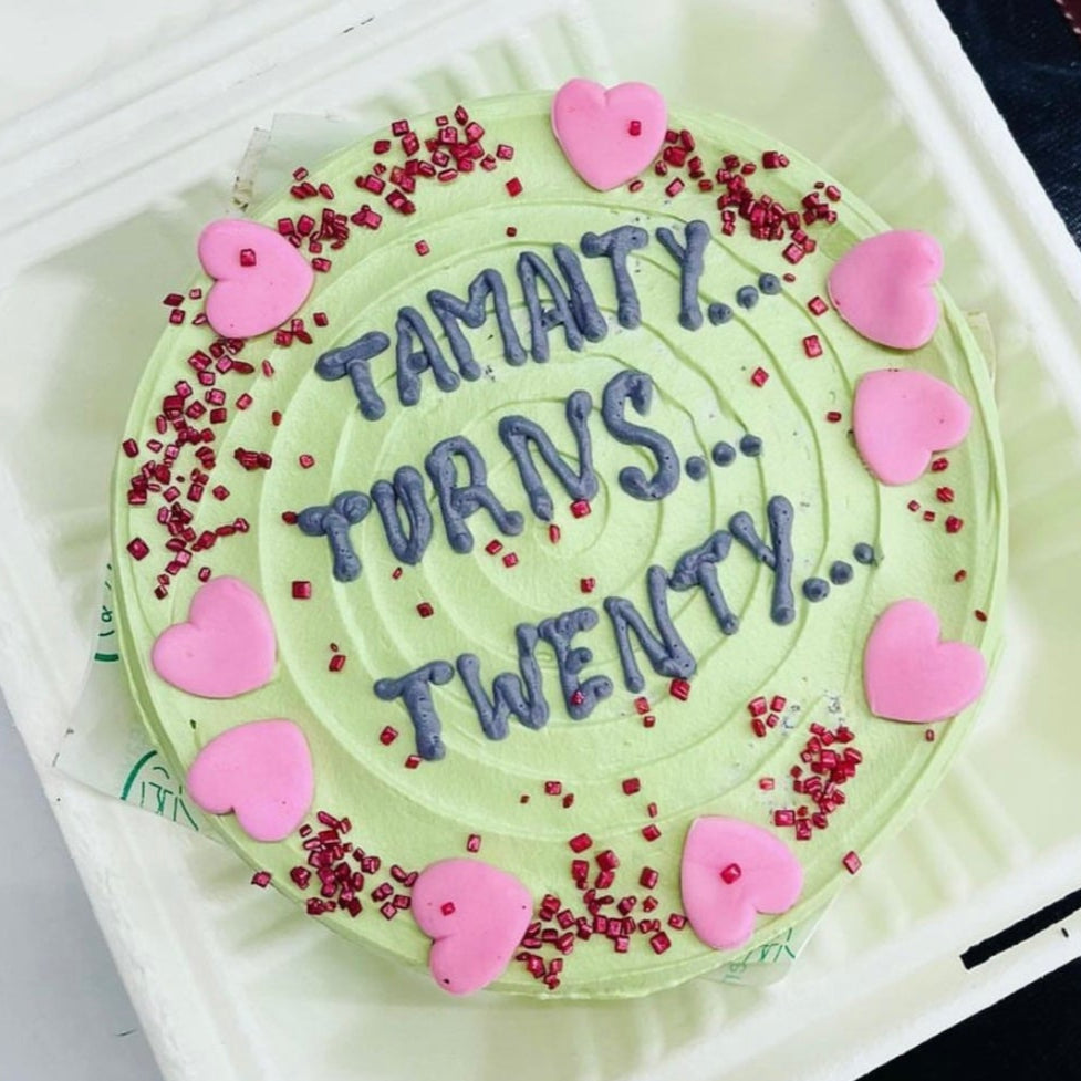 Pretty designed light green birthday cake having little pink hearts around it.