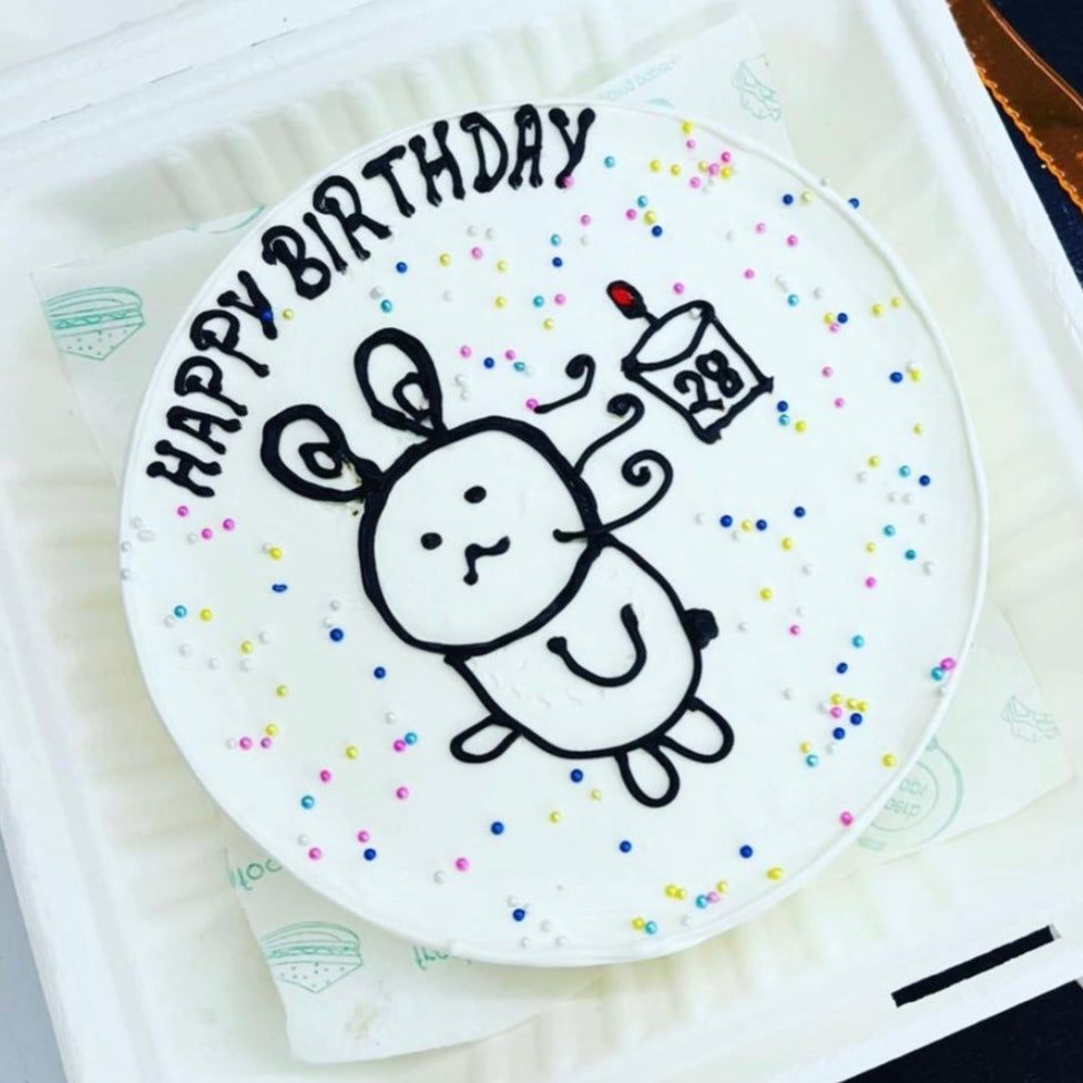 A birthday cake inside a box, beautifully decorated with a cartoon theme on top.