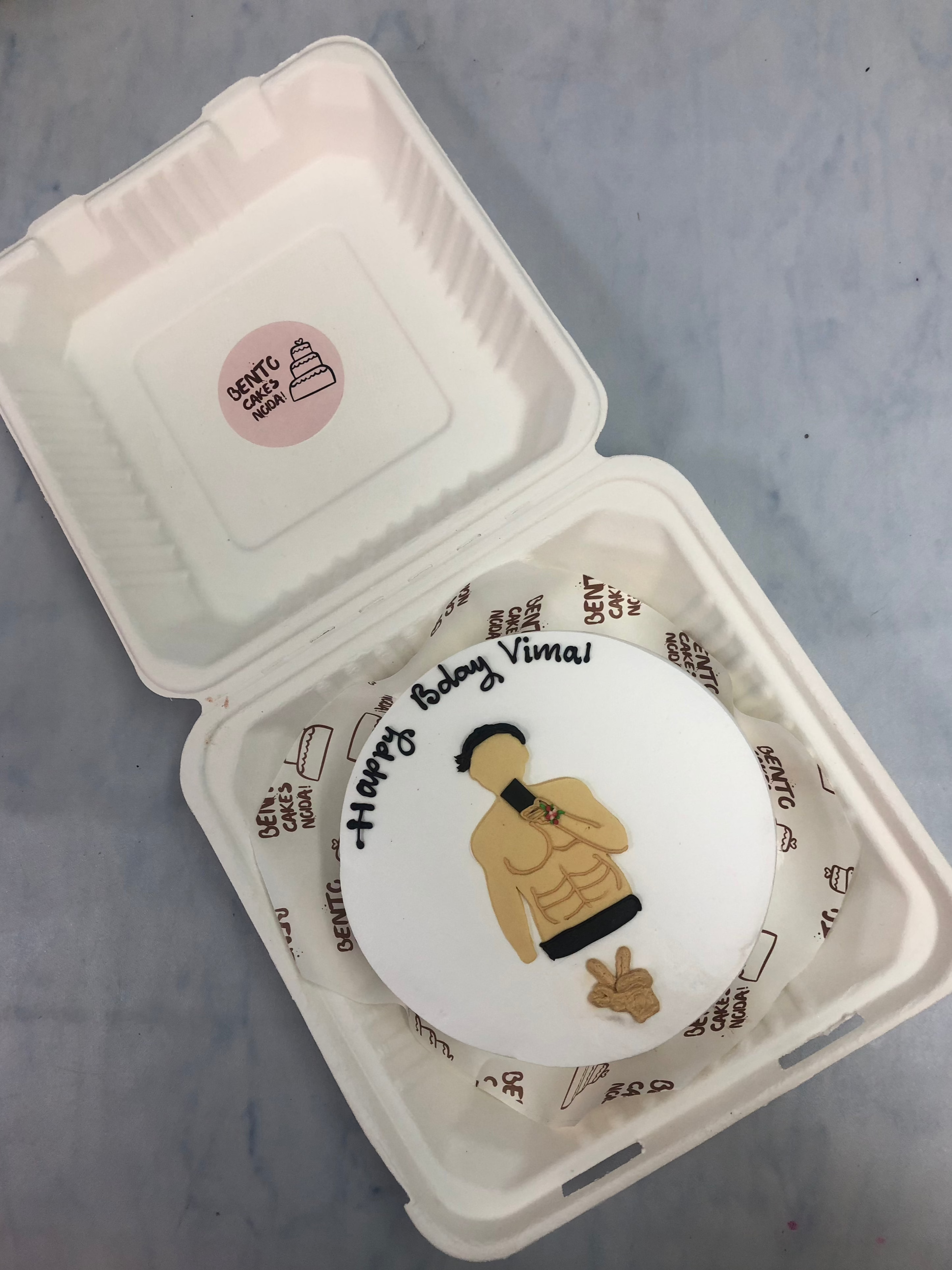A white bento cake is designed for a body builders birthday.