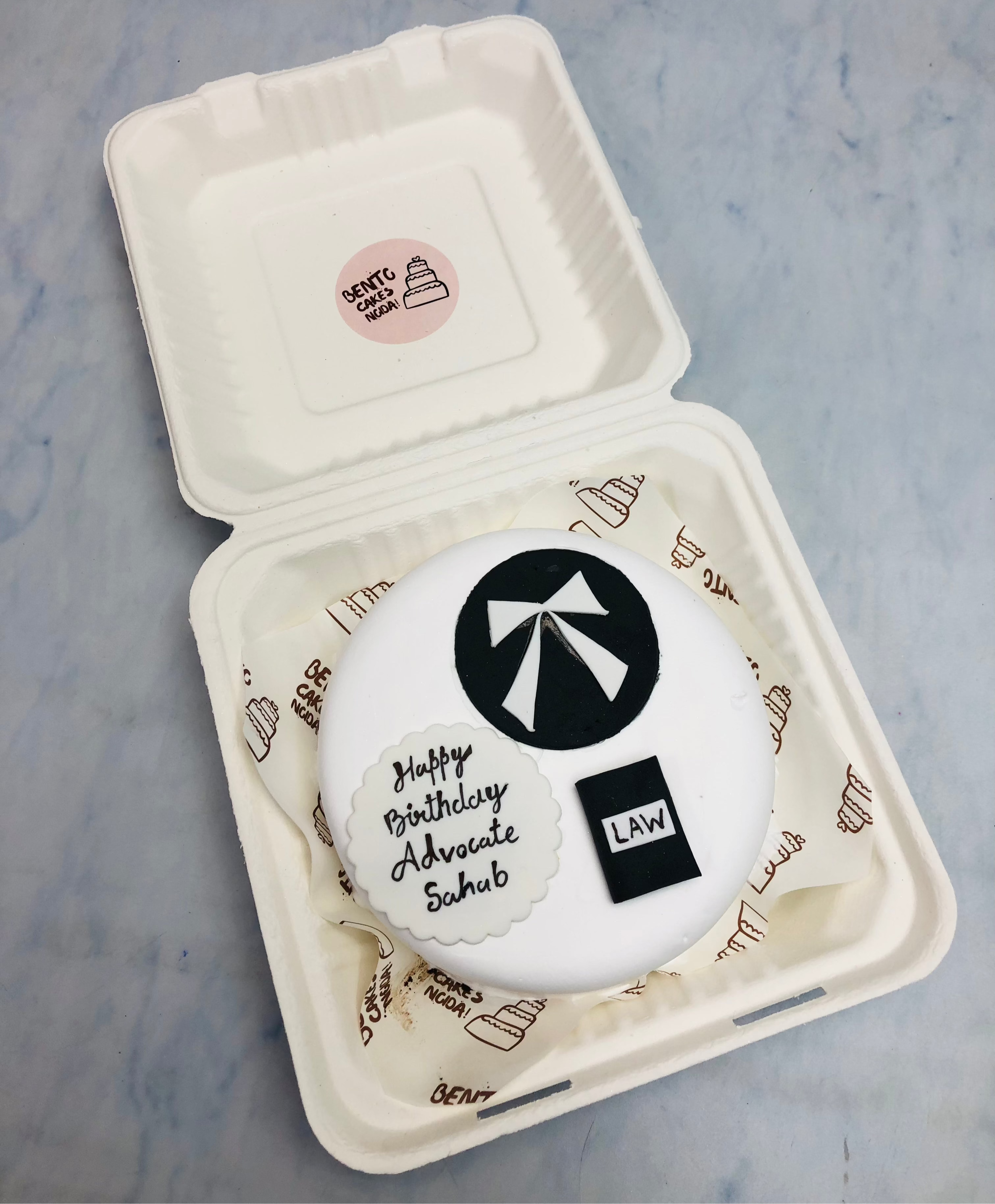 A white bento cake is designed for lawyers birthday with law book and batch etc. design.