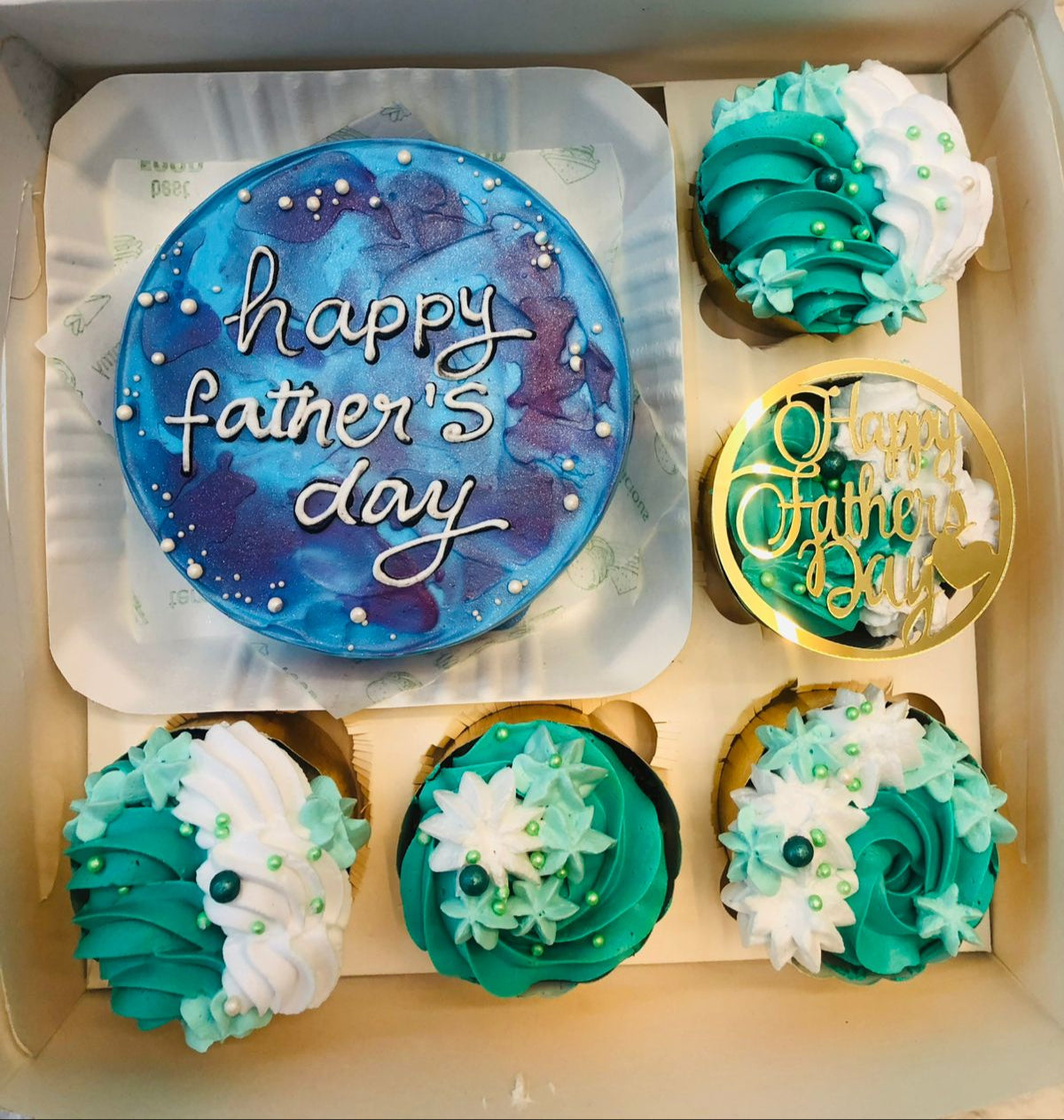 An aesthetic blue bento cake with 5 cupcakes of white green floral design.