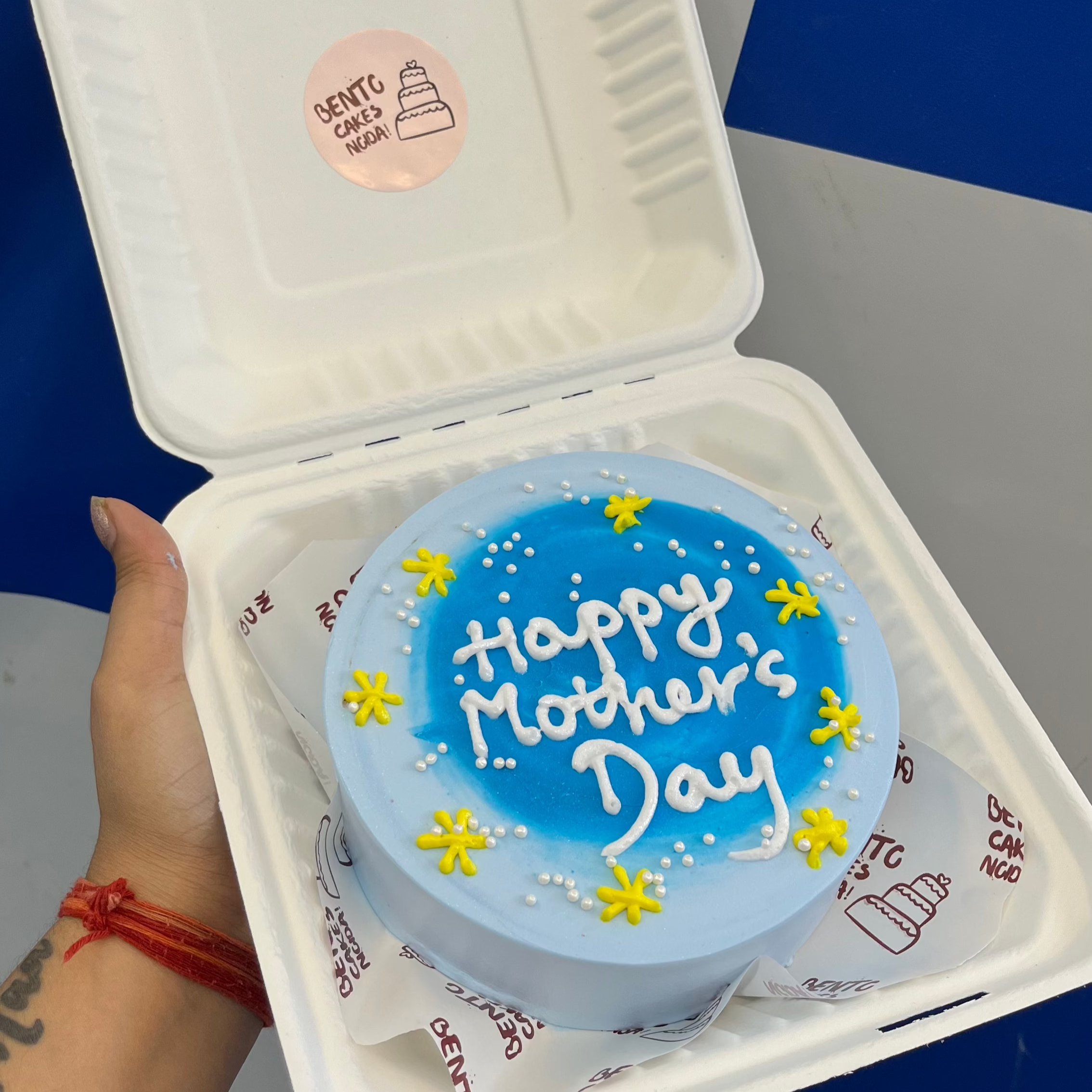 Aesthetic blue bento cake is designed with yellow florals design for Mother's Day.