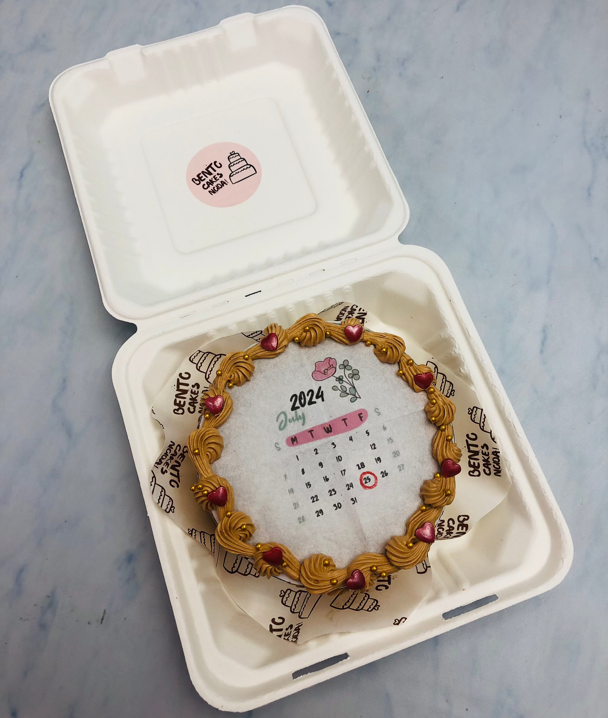 A brown fire bento cake with a calendar fire paper design and decorated with dark red hearts.
