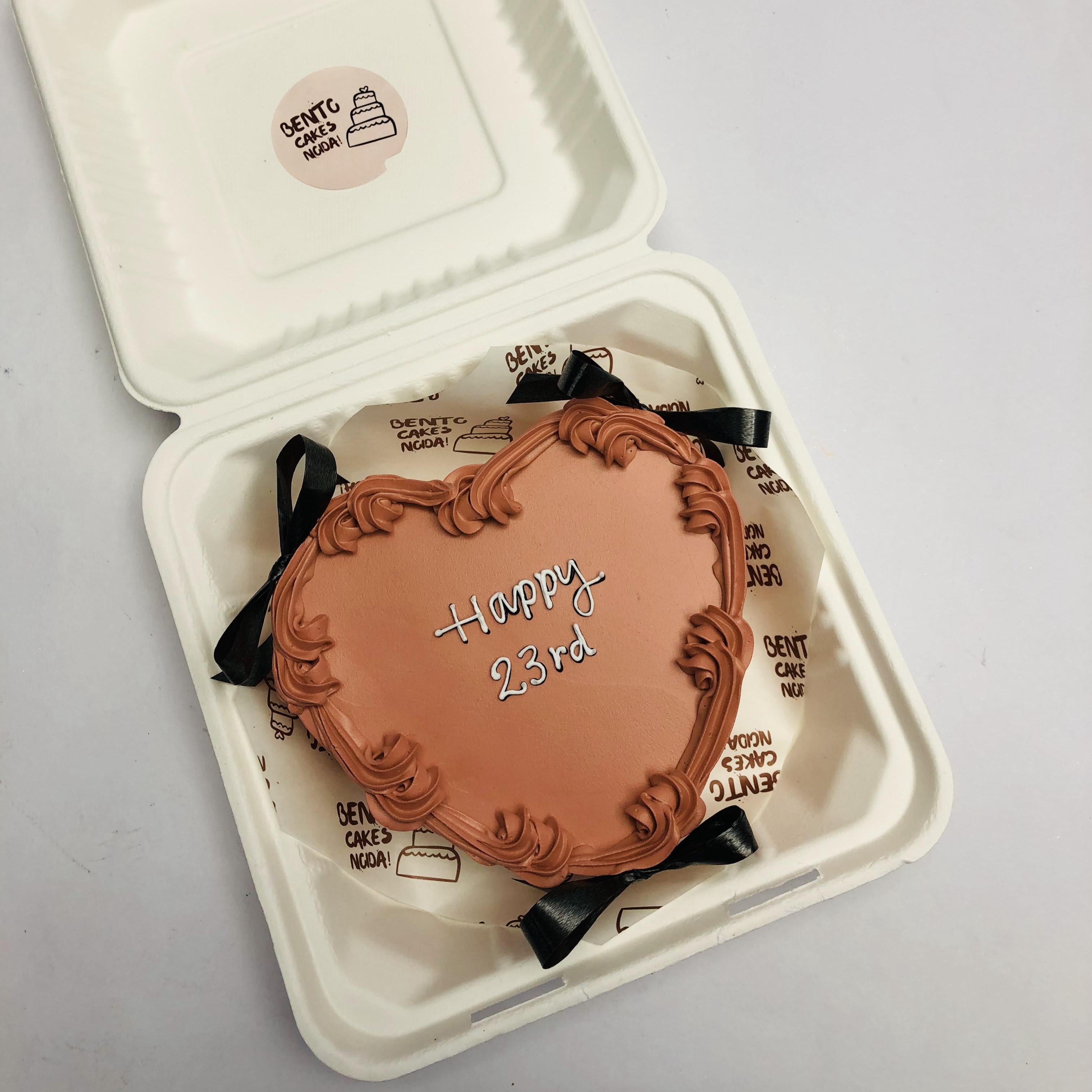 A brown color heart shape cake with black bows.