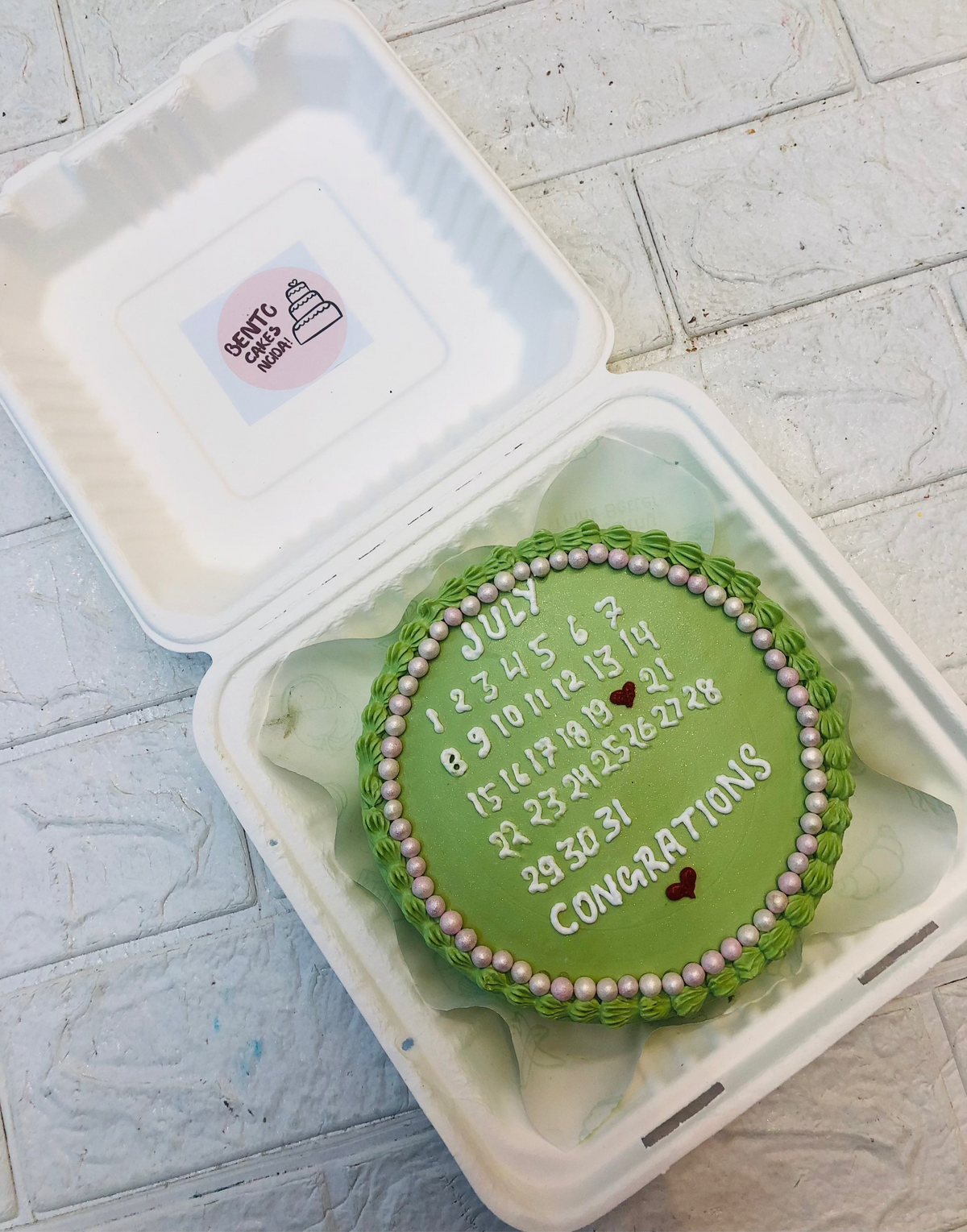 A shiney green calendar theme bento cake with congratulations message.