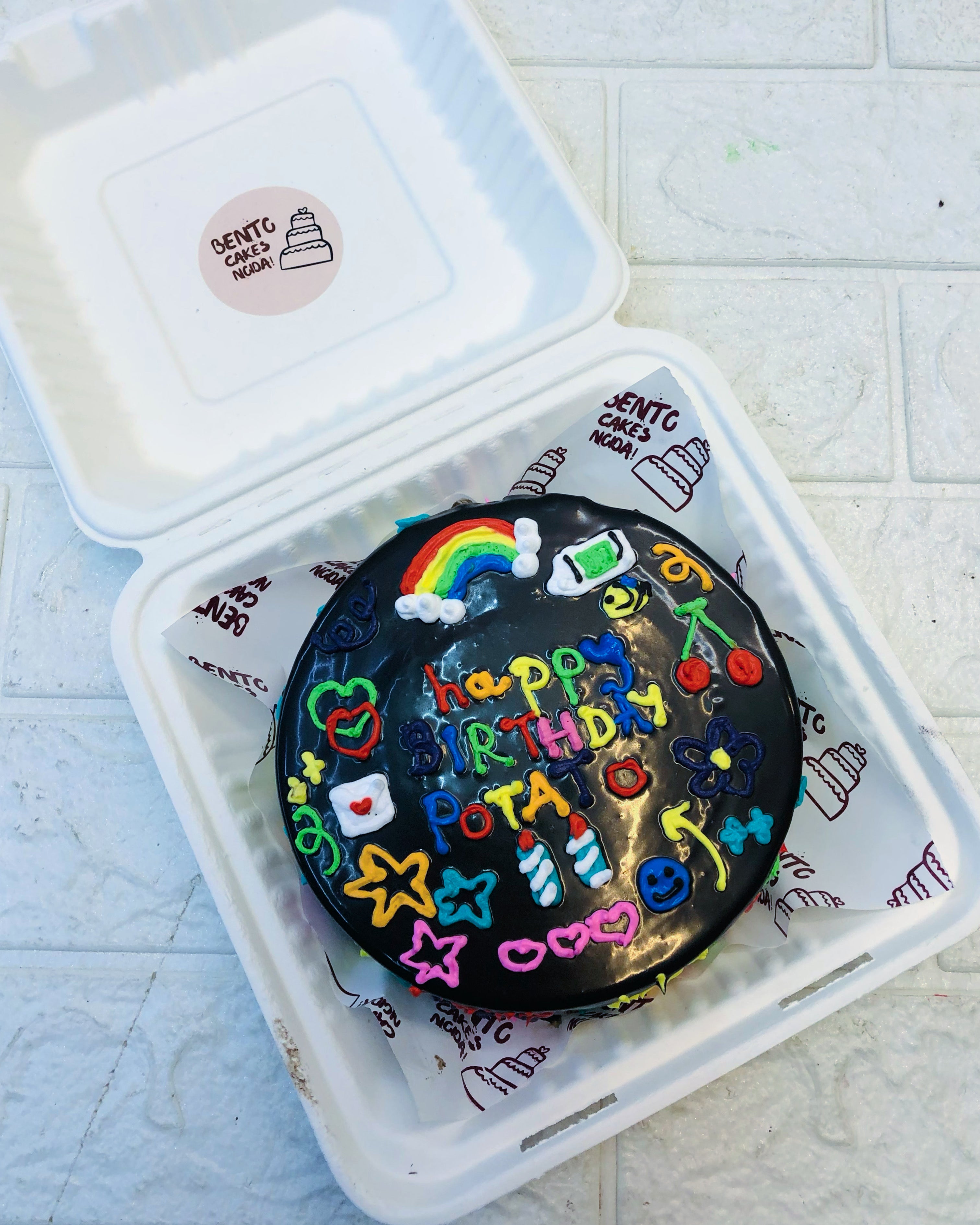Black chocolate bento cake having colorful drawing.