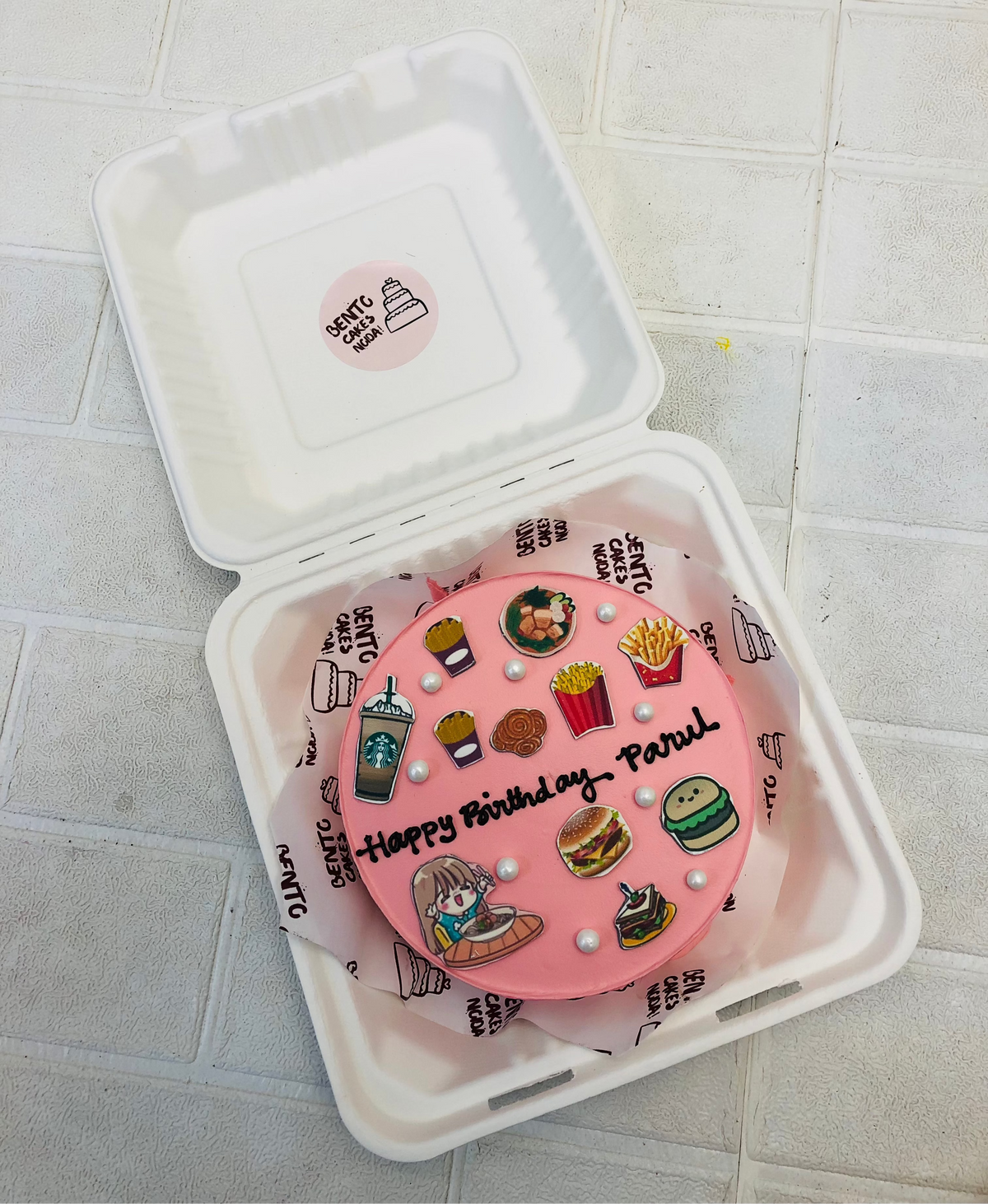 A peach color bento cake is designed on a foody girls birthday with all her favourite items printed on the cake.