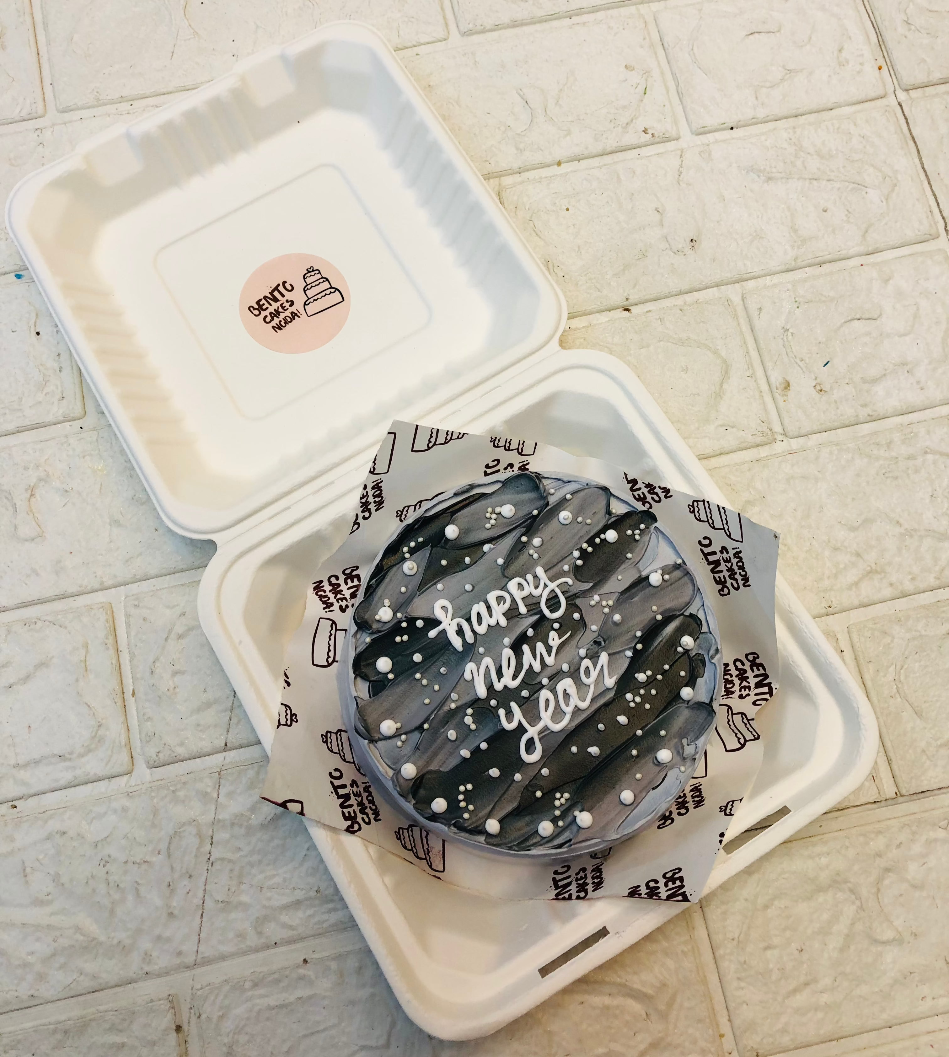 Aesthetic grey bento cake with black shades on top and decorated with white sprinkles for New Year Celebration.
