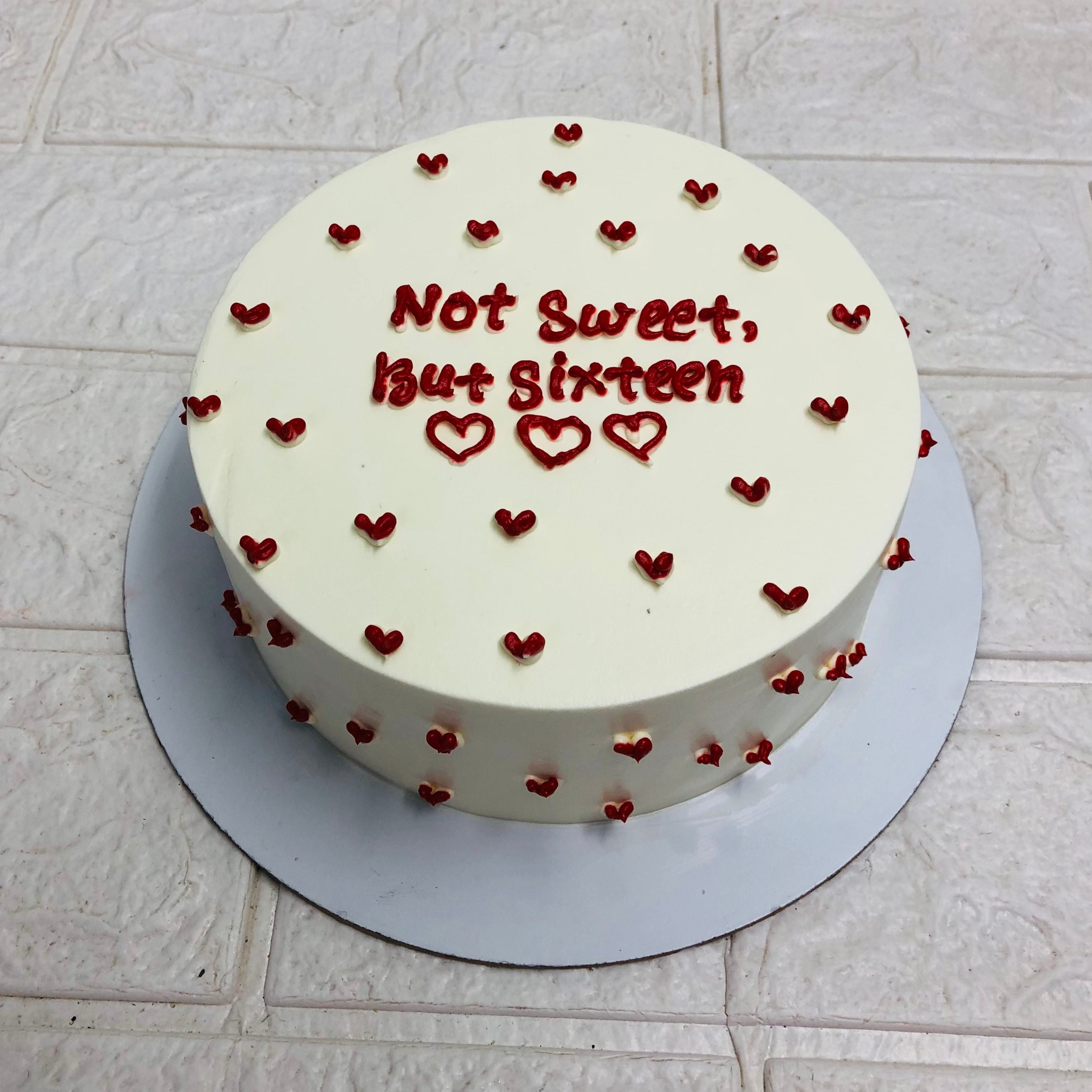 A round white cake is beautifully covered with red hearts design on it and a text "Not Sweet But Sixteen" beautifully written with red icing. 
