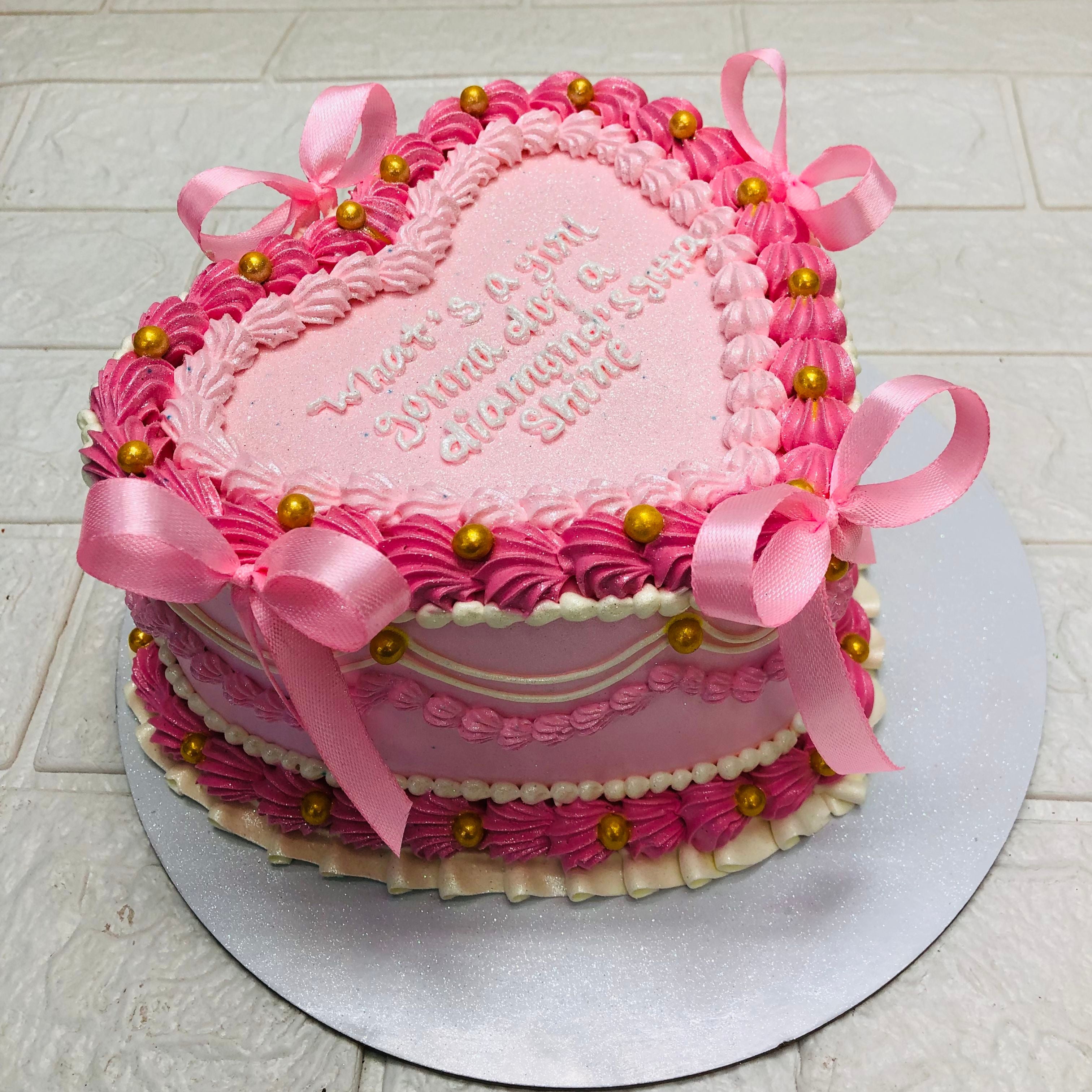 A pink heart-shaped cake adorned with a delicate ribbon bow, perfect for celebrations and special occasions.