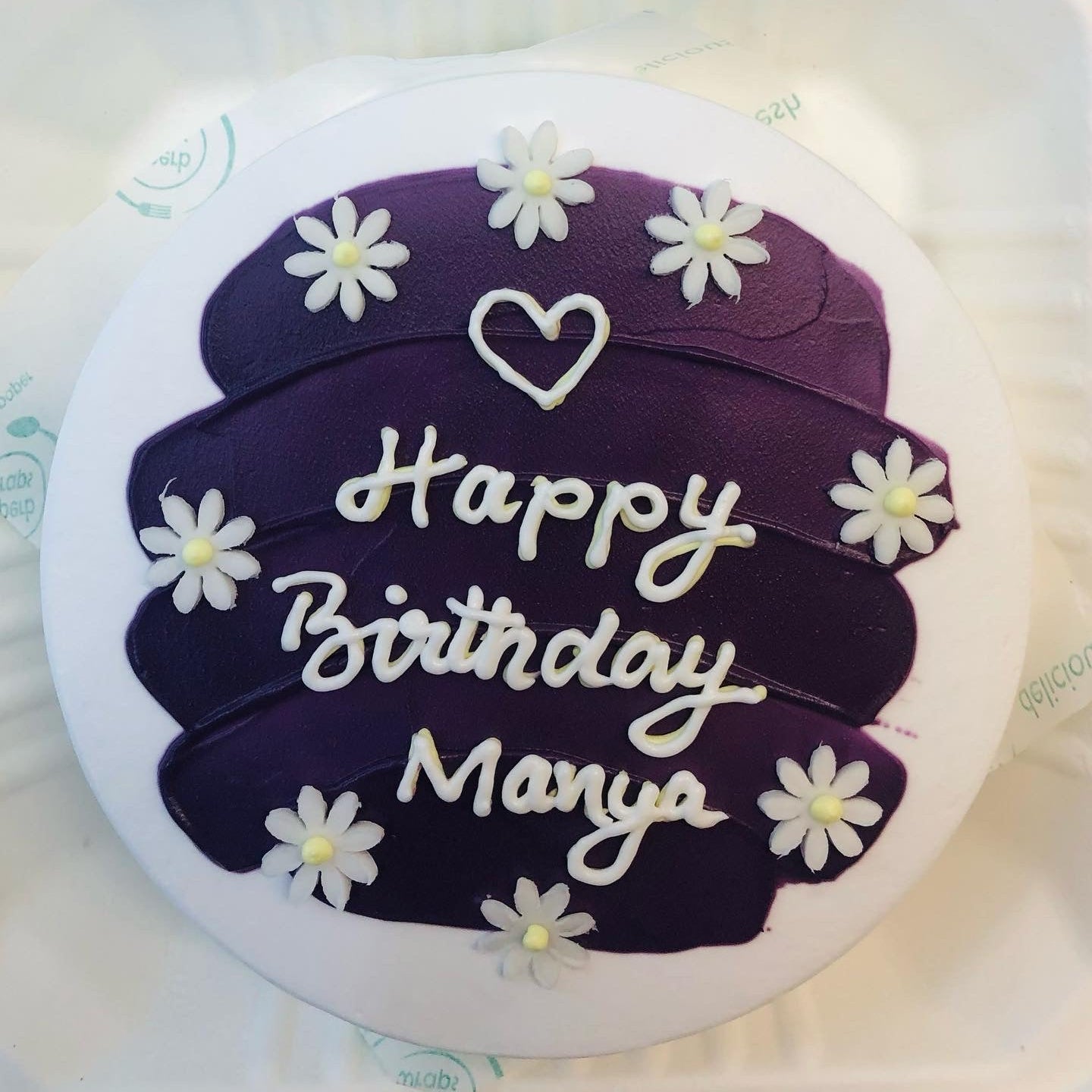 A purple shades on white bento cake with white fondant florals on it for birthday celebration.