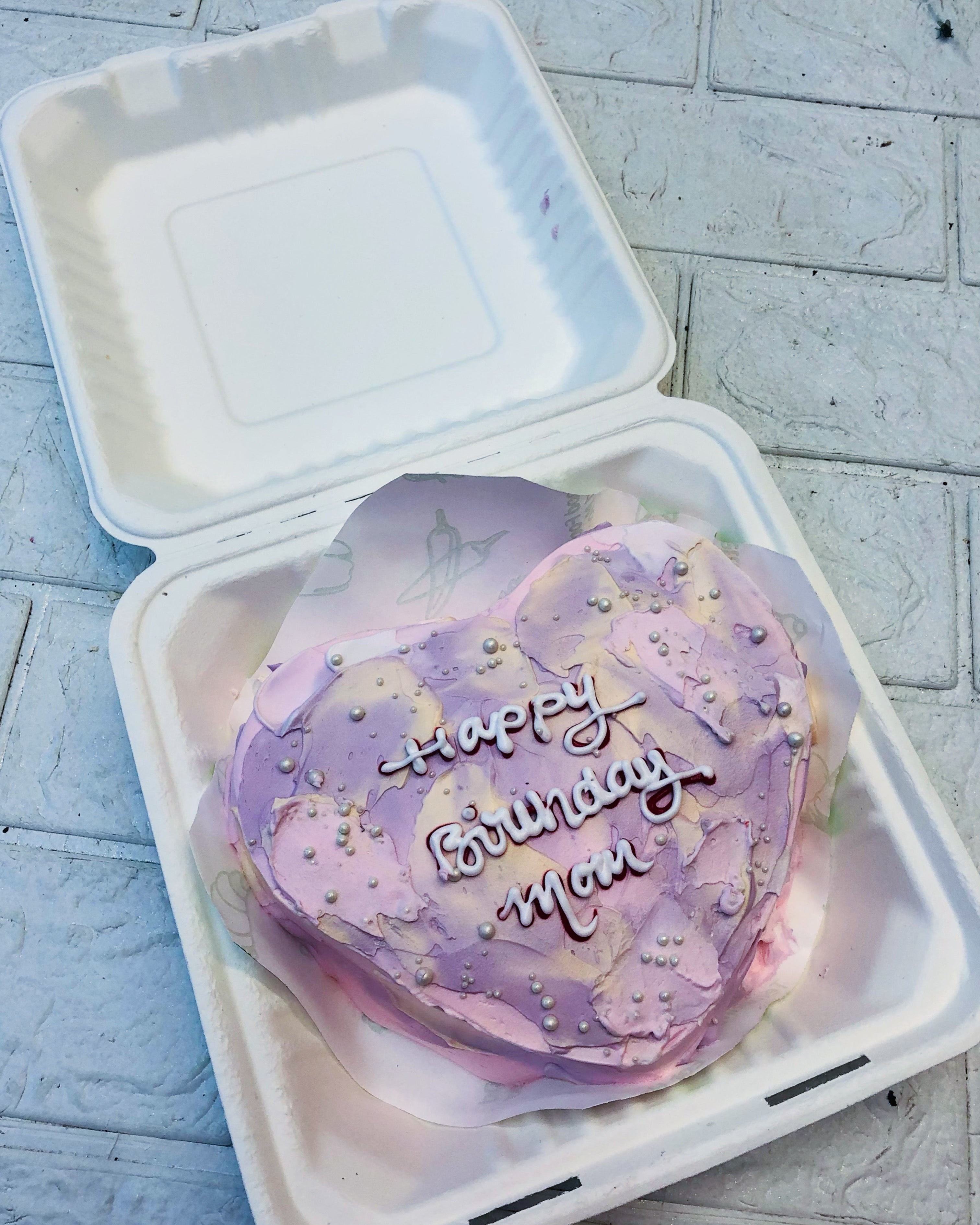 A Aesthetic Purple Heart Shape Bento Cake with aesythetic pink shades and deorated with silver sprinkles.