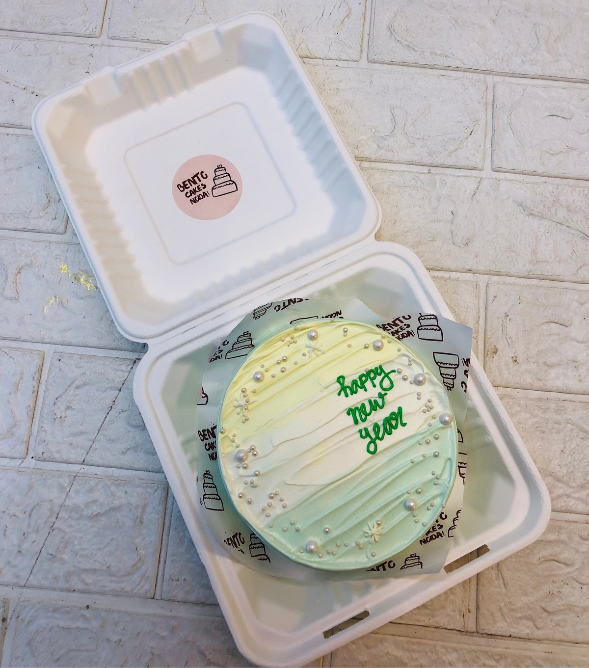 Aesthetic multicolor bento cake having a text of Happy new year ioth green color on it.