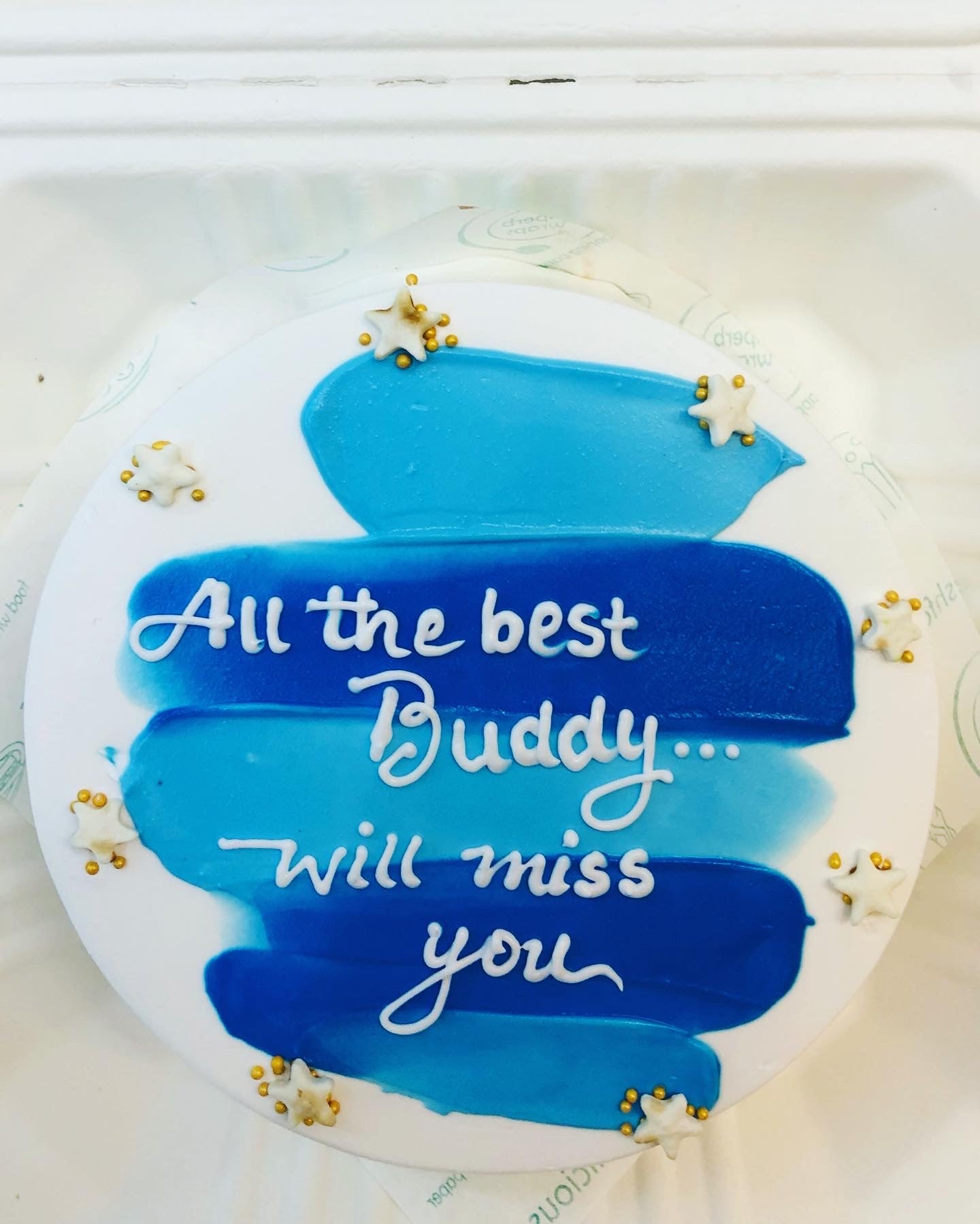 A white cake decorated with blue icing on it and a text written on it.