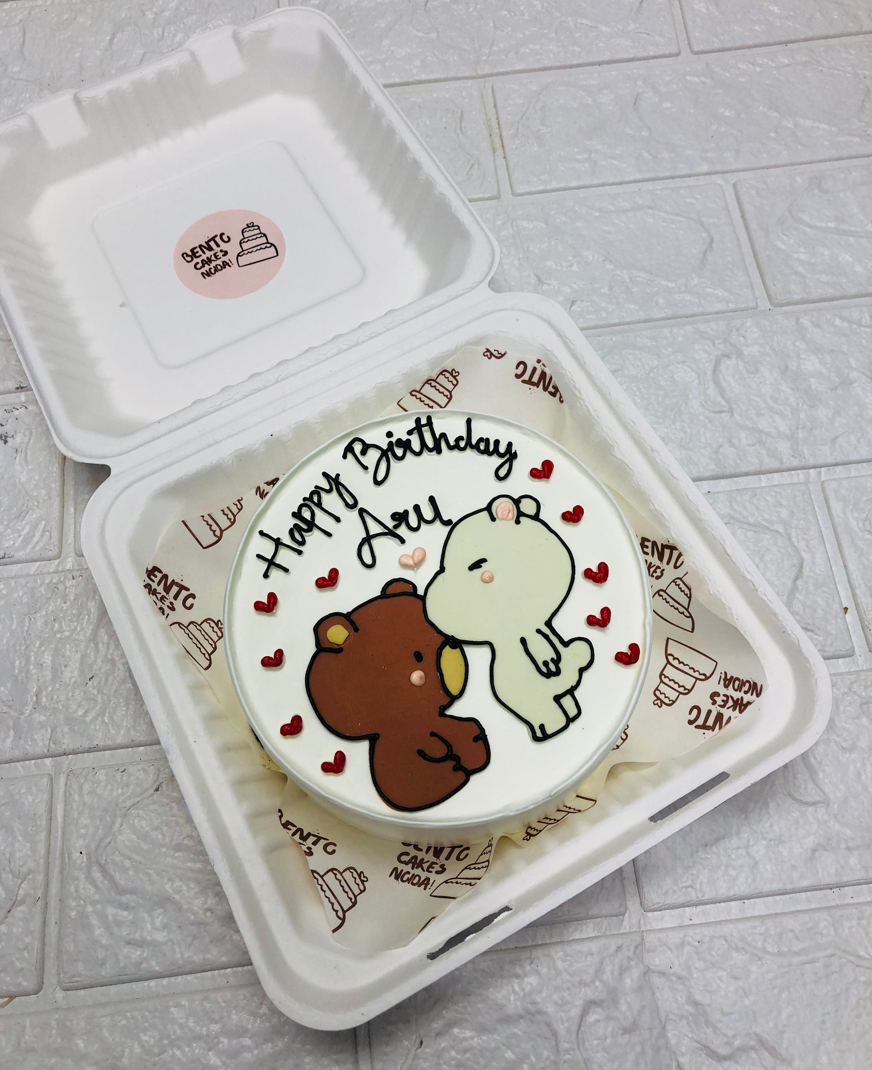 A white bento cake with kissing bubu dudu drawing and filled with red hearts.