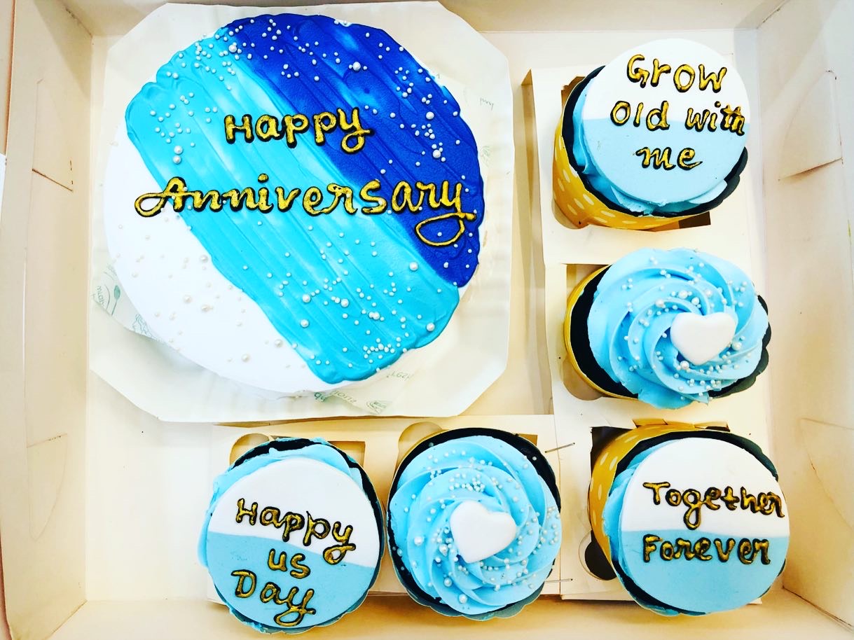 A cake in a bento box is added with 4 cupcakes and is made for anniversary occasion.