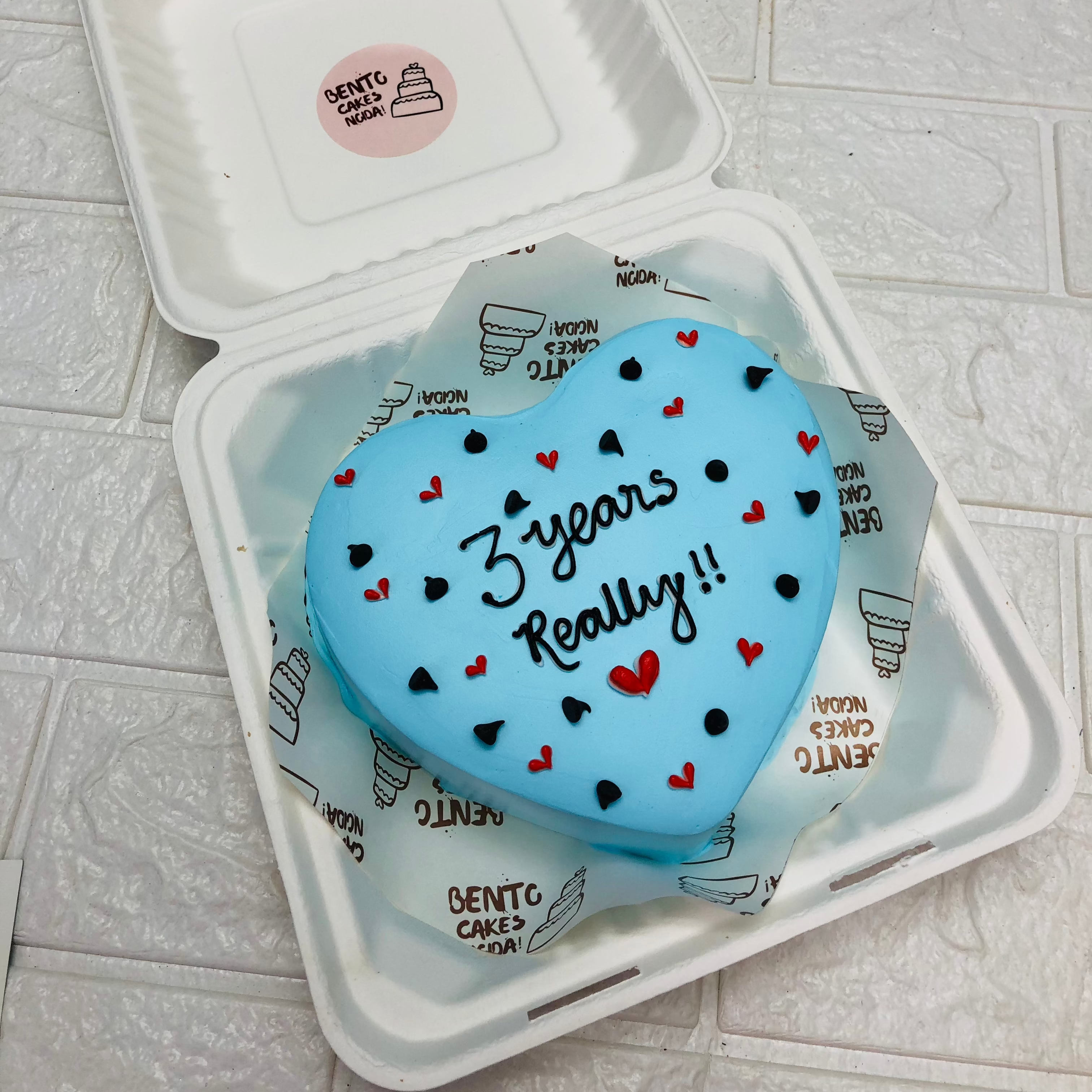 A skyblue color heart shape bento cake with pretty red and black hearts design all over the cake.