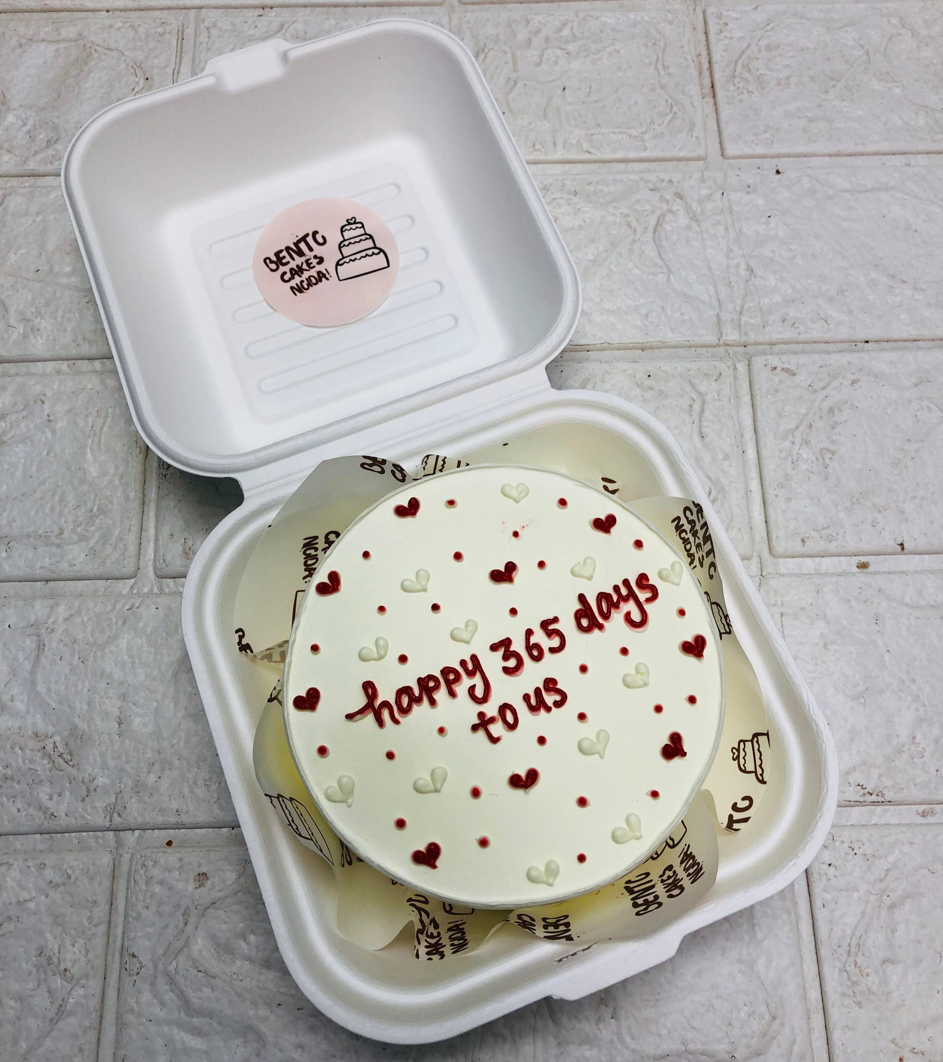 A pretty white mini bento cake is designed with red and white hearts for 1st anniversary. 