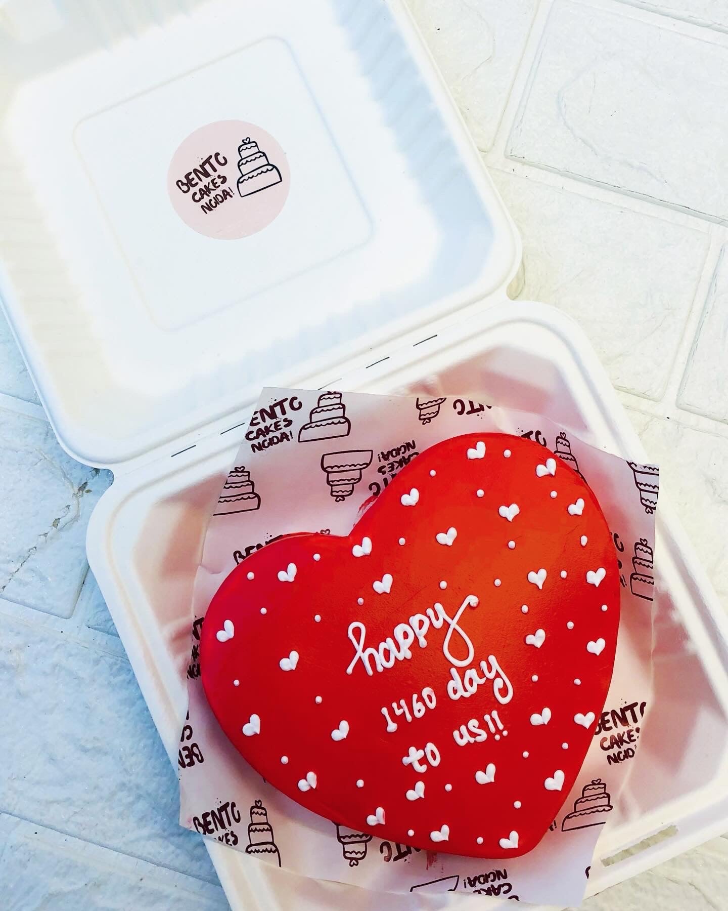 A dark red icing heart shape cake with little hearts design in white color all over the cake.