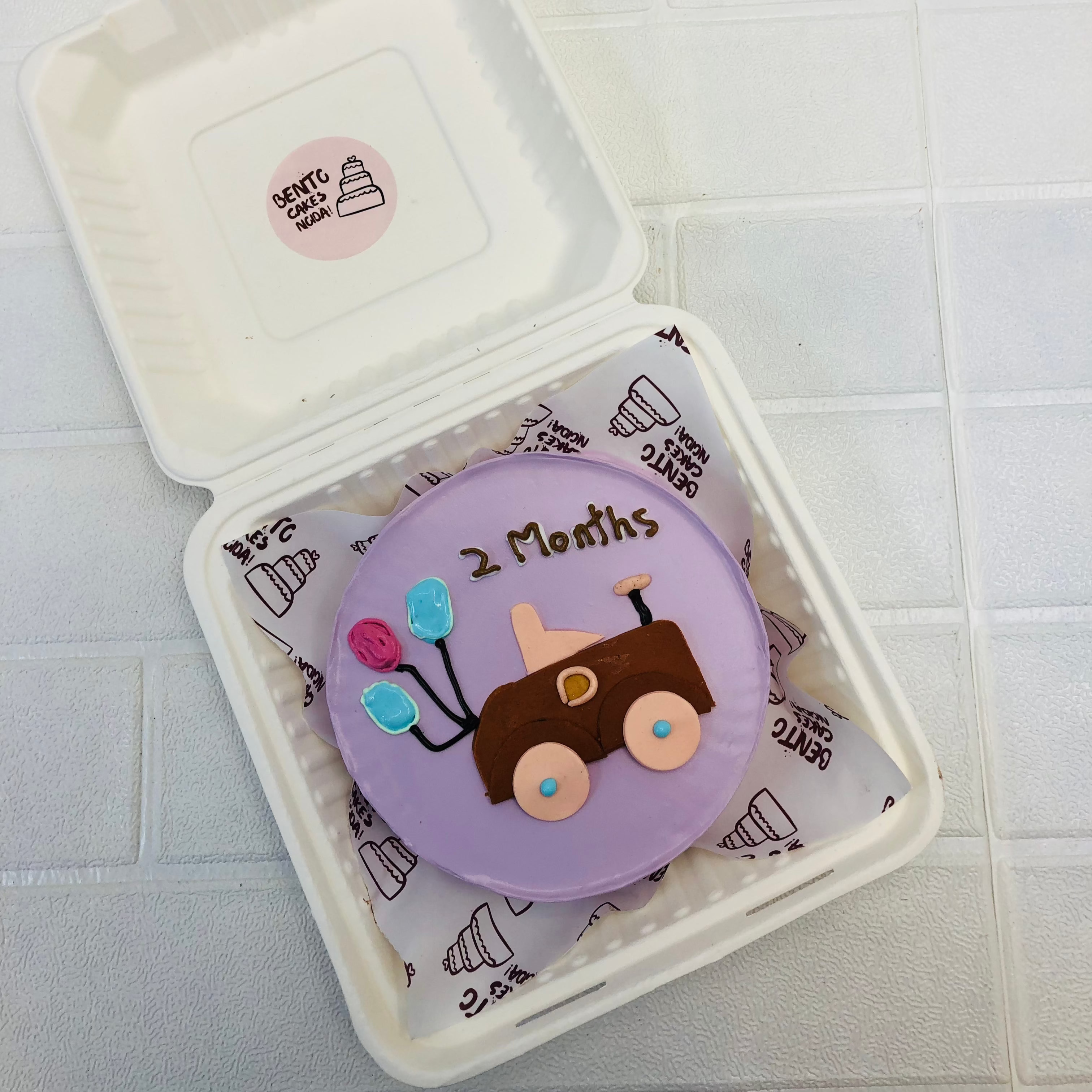 A light purple cake with a toy car design for 2 months baby.