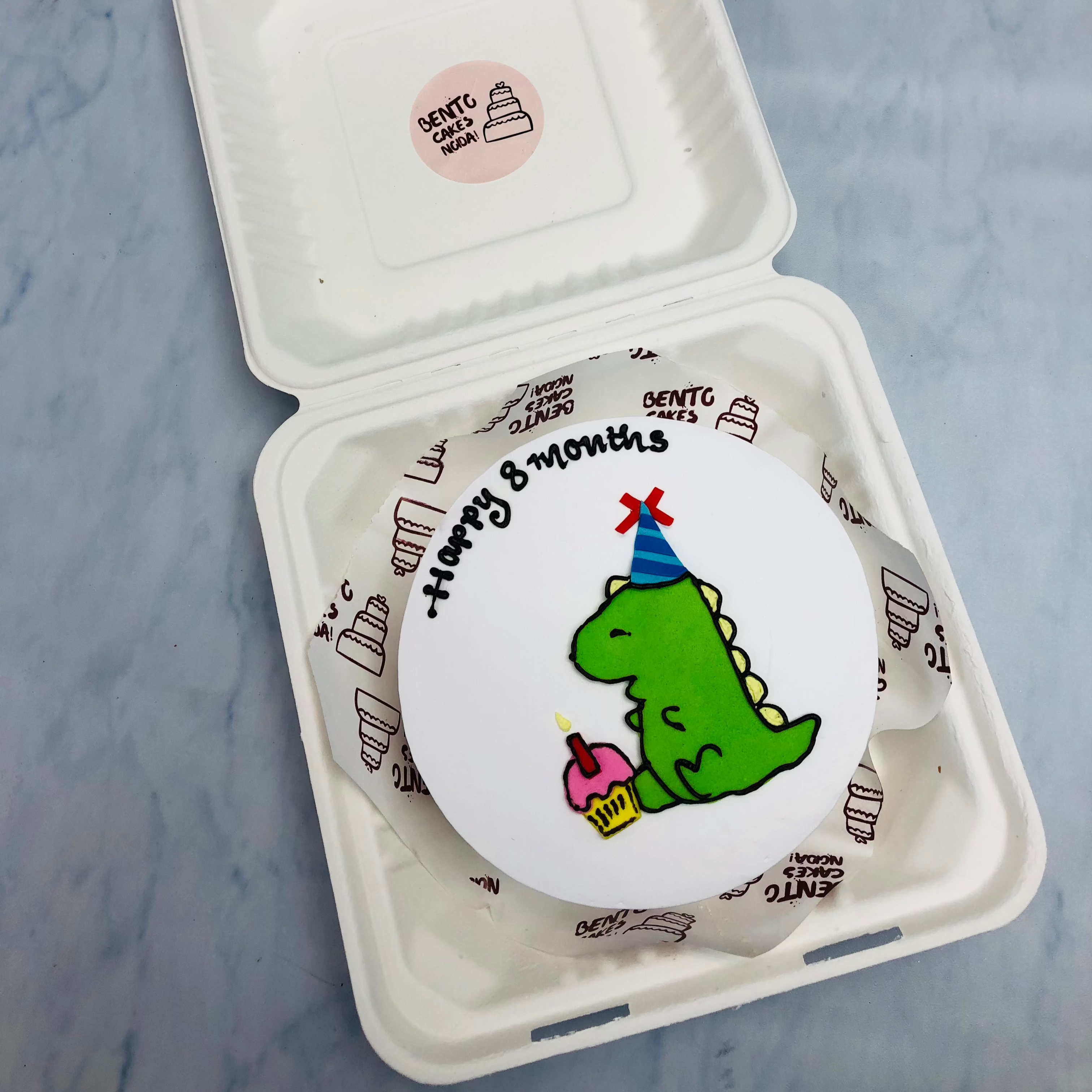 A white bento cake with cute baby dainosauors design on cake.