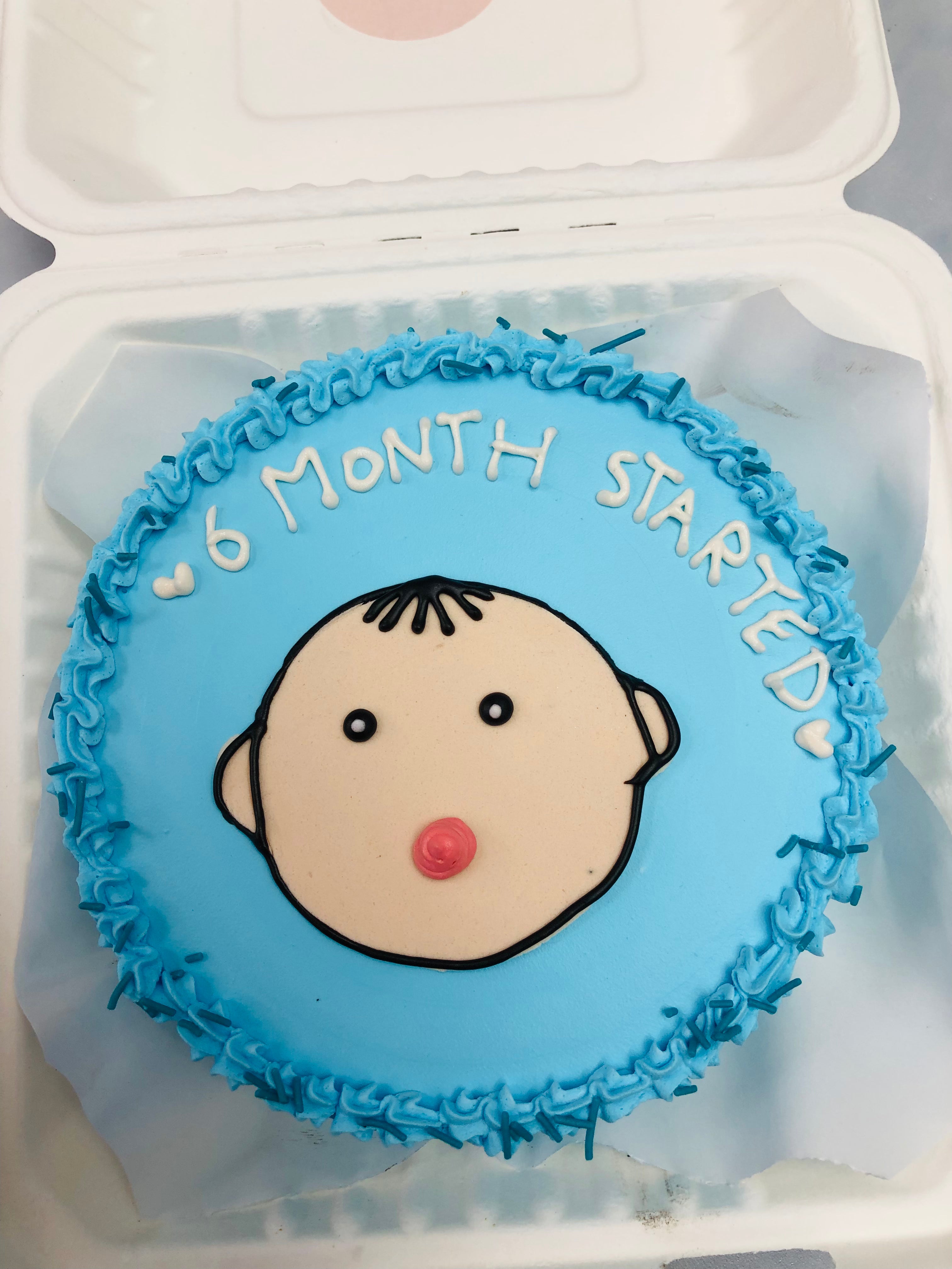 A sky blue round cake in a bento cake with a baby dace design