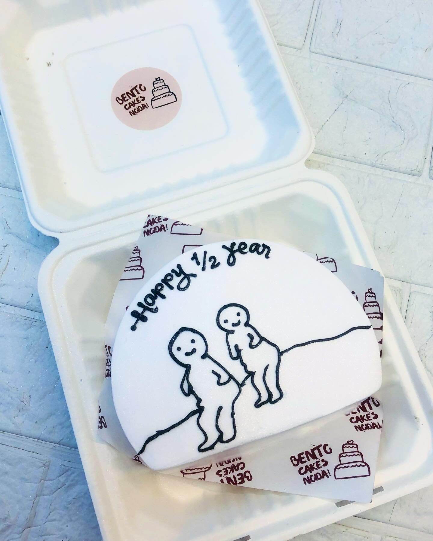 A white half shape bento cake with 2 cartoon characters design for 6 months baby.