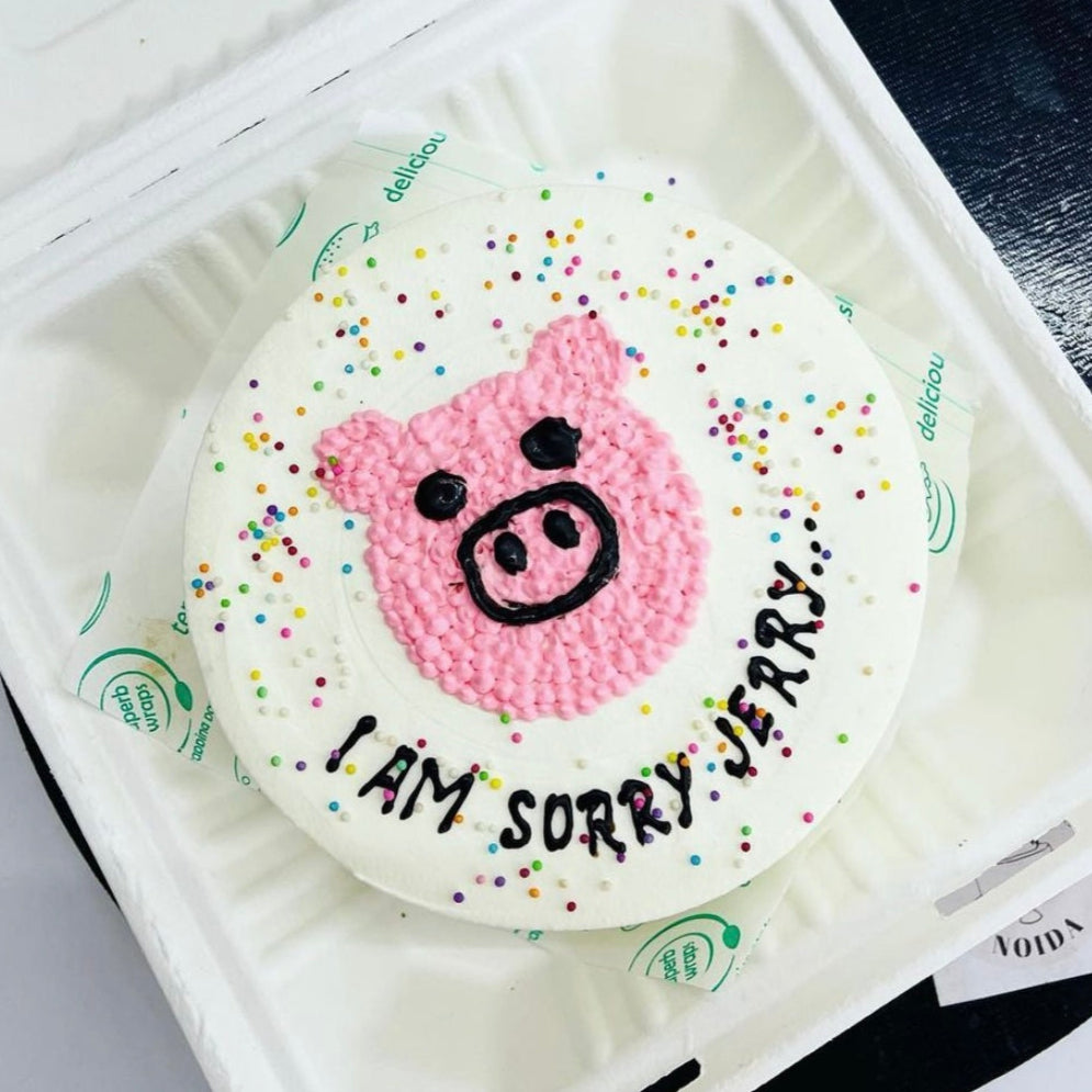 A cake designed to resemble a bear's face, presented in a Styrofoam box for storage or transport.