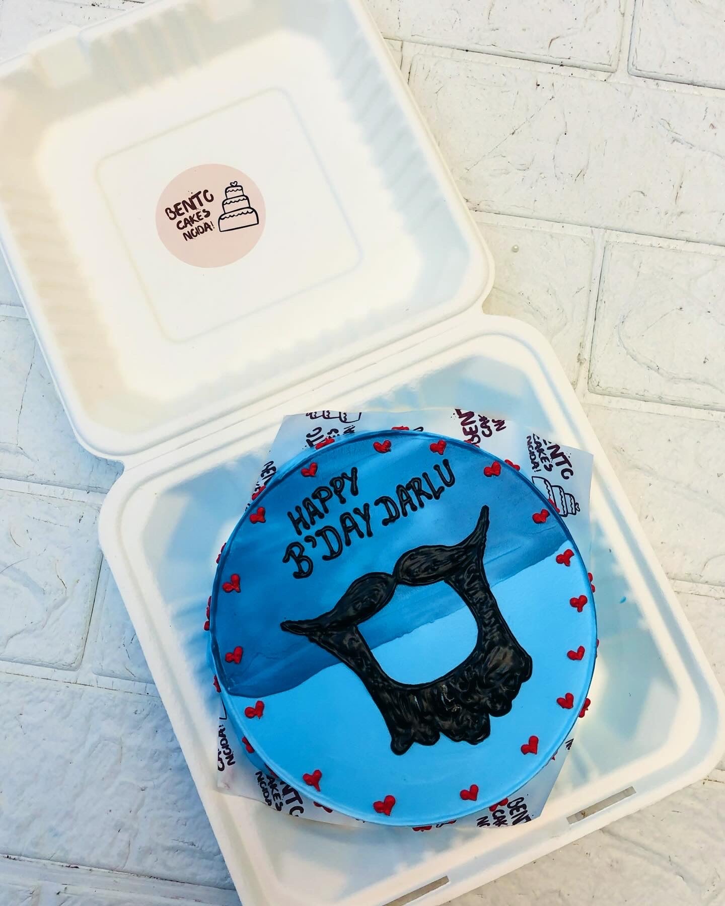 A blue bento cake is designed with a mens french beard design for birthday occasion.