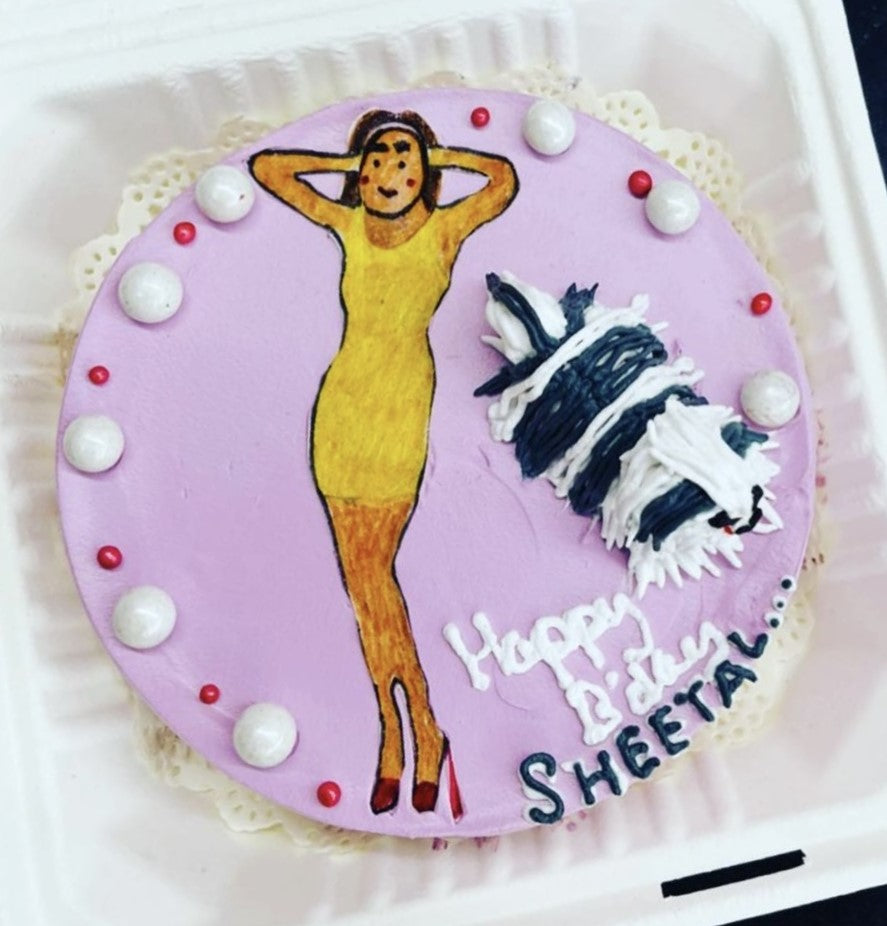 A beautifully decorated cake featuring a woman in an elegant dress, showcasing intricate details and vibrant colors.