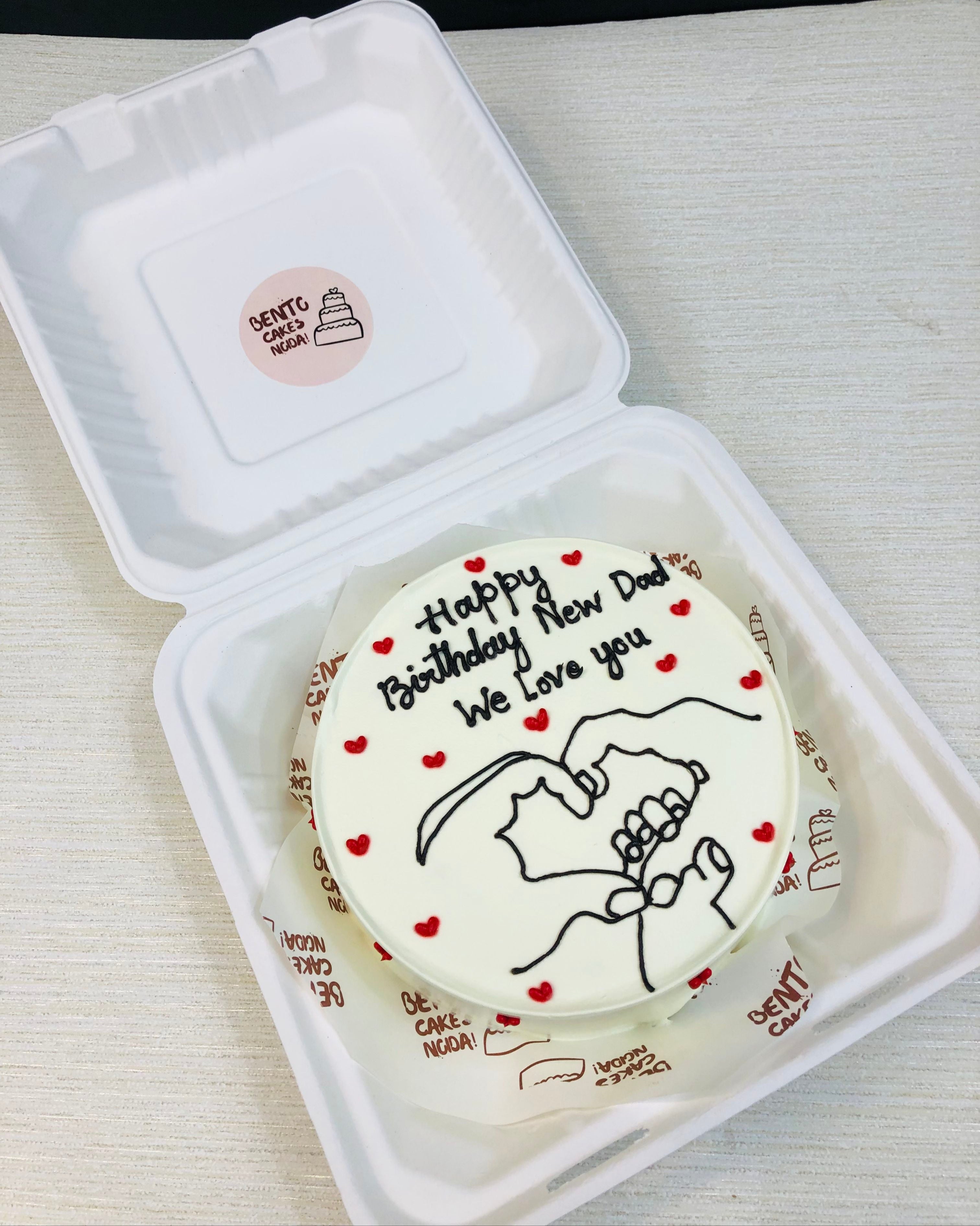 A white bento cake designed with family hands toether drawign of father, mother and baby. This bento is designed for becoming a dad theme.