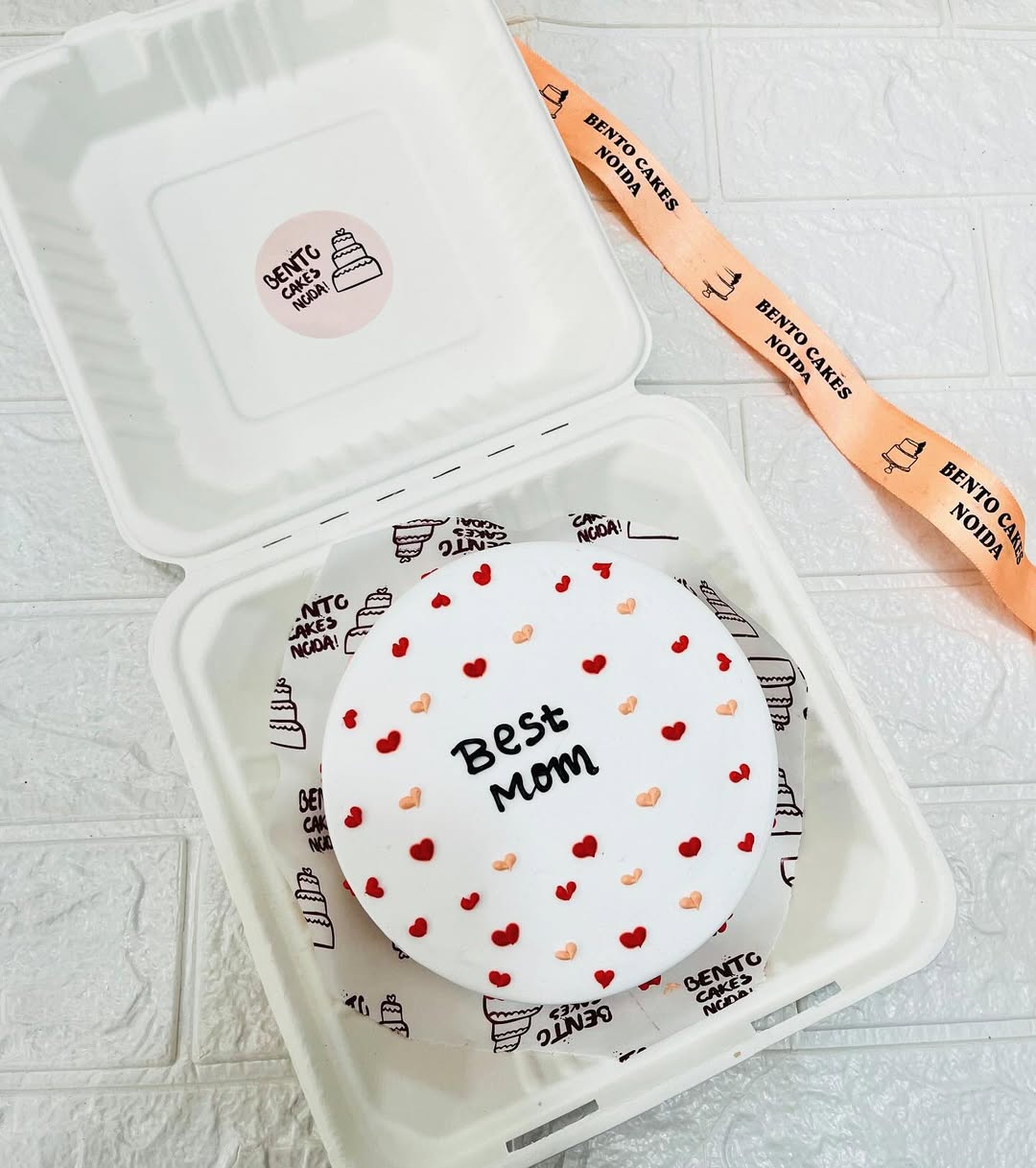 A white cake with little red and pink hearts design all over cake.