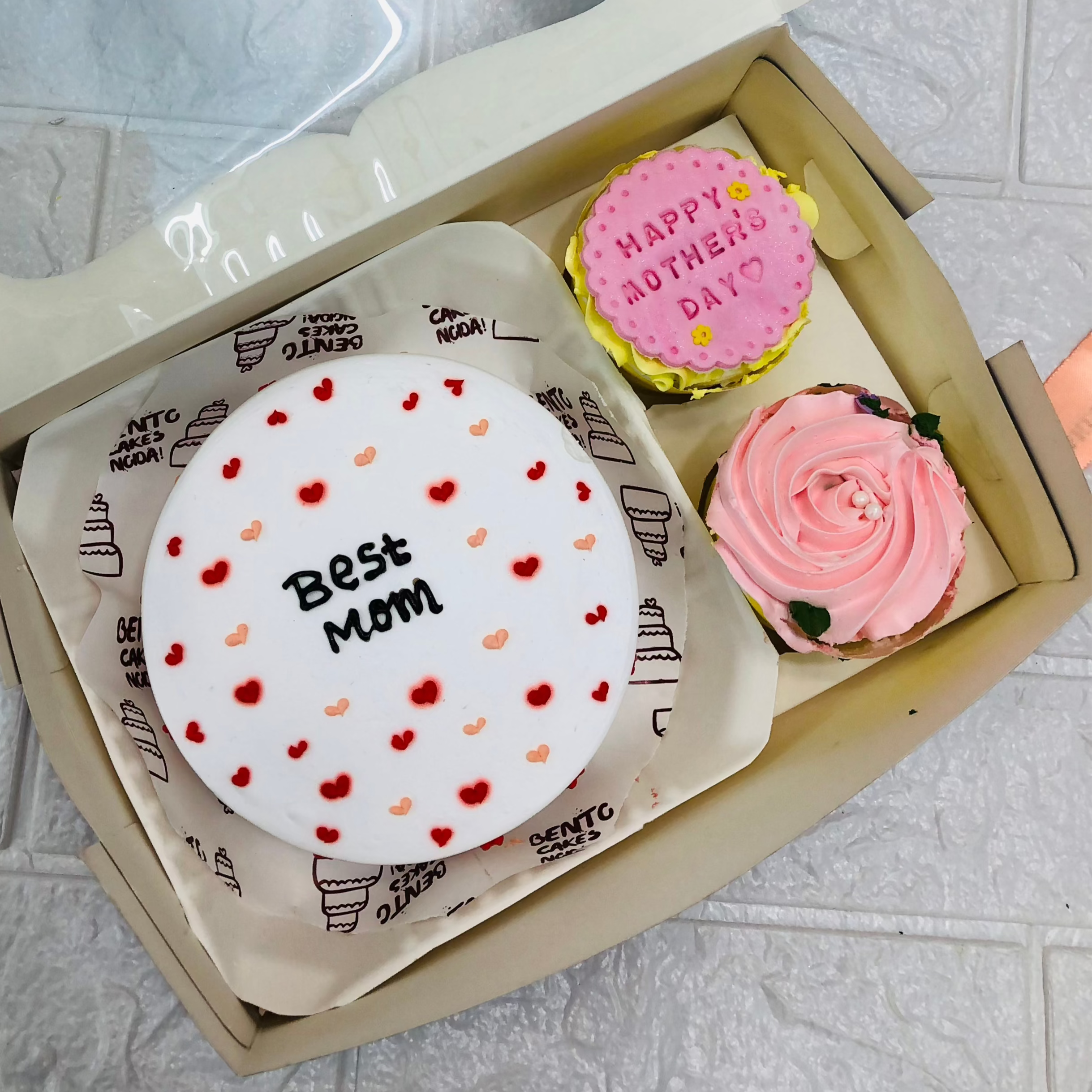 A mini cake combo having a cake and 2 cupcake sets. A white cake with hearts design for Mothers Day and cupcakes having floral and fondant design.