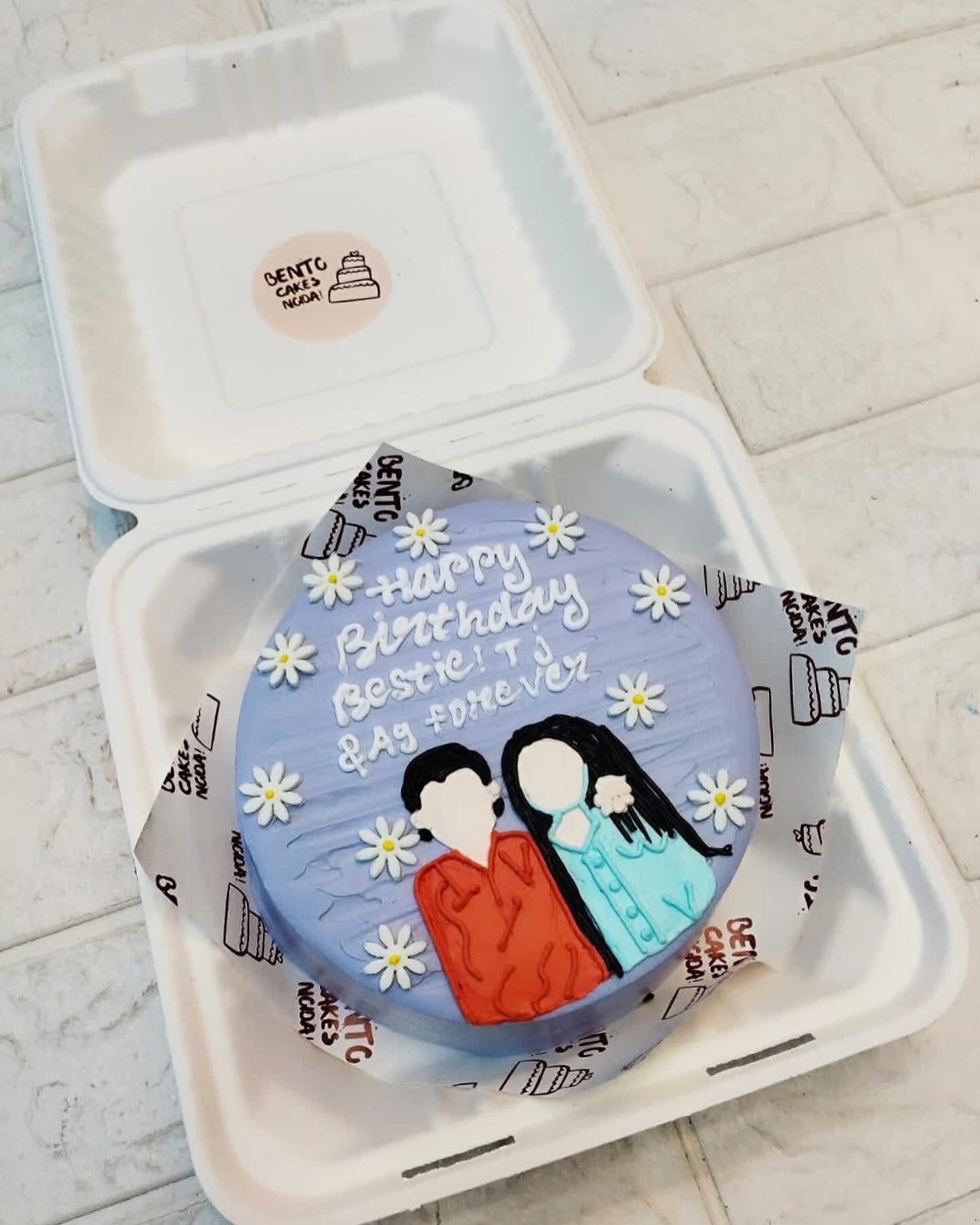 A floral blue bento cake shaowing a boy and a girl together celebrating herv birthday.