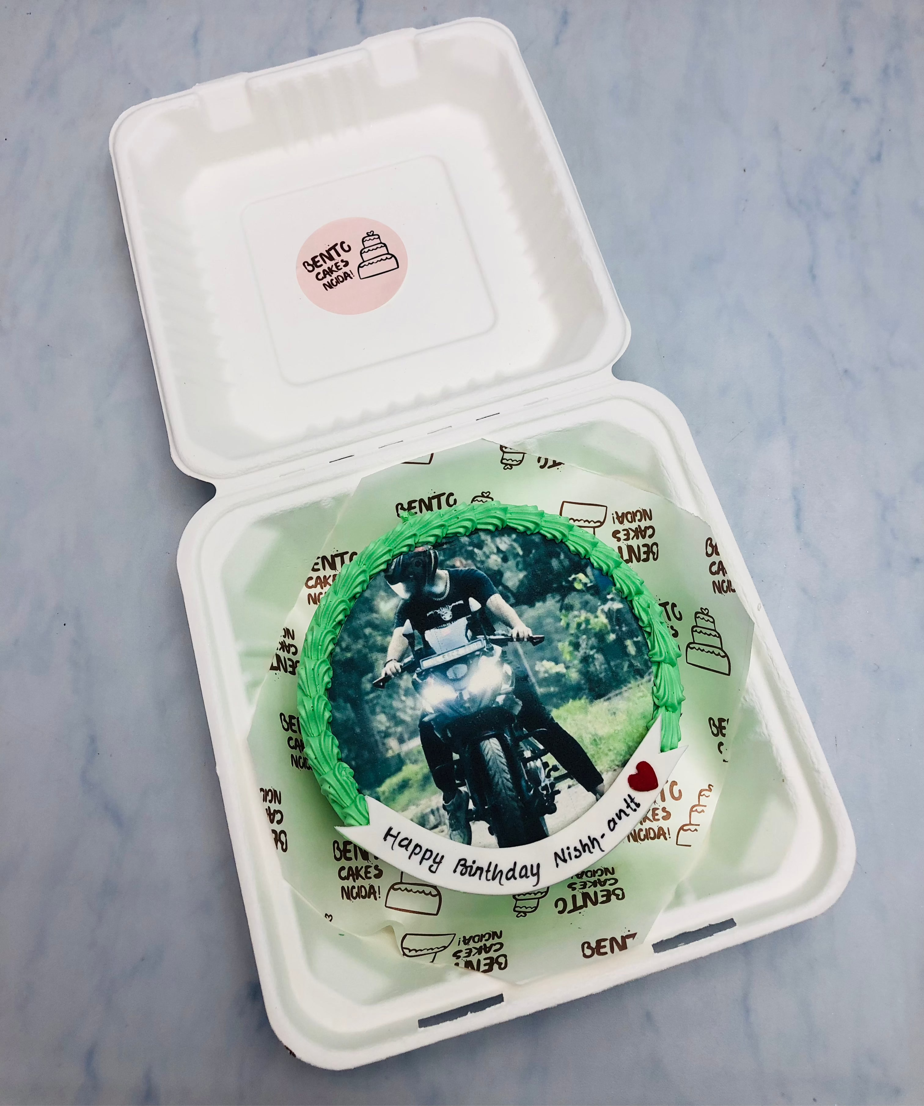 A green bento cake with a biker bo photo on the cake.