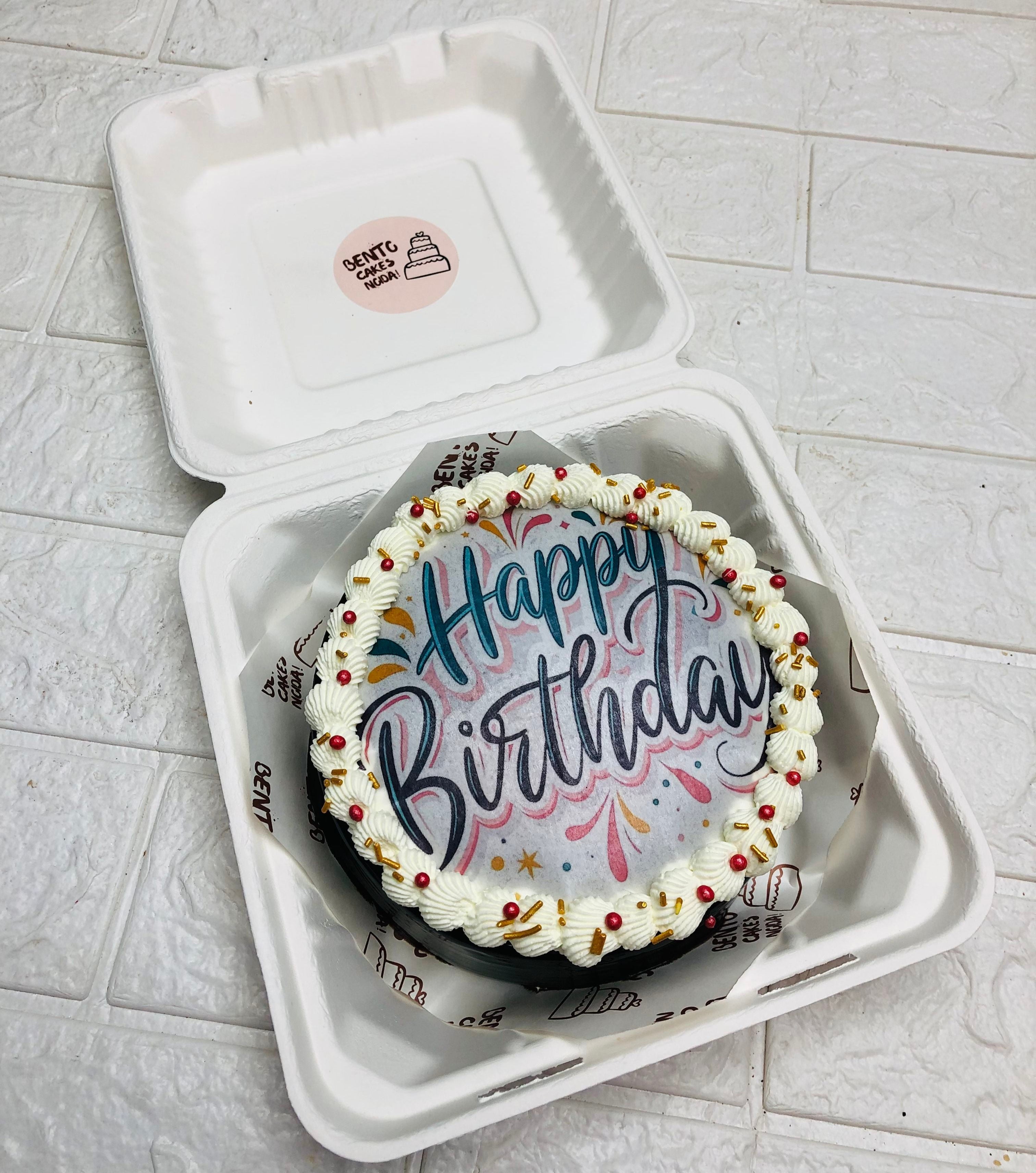 A chocolate cake with a fire paper of happy birthday and beautifully decorate with red sprinkles.