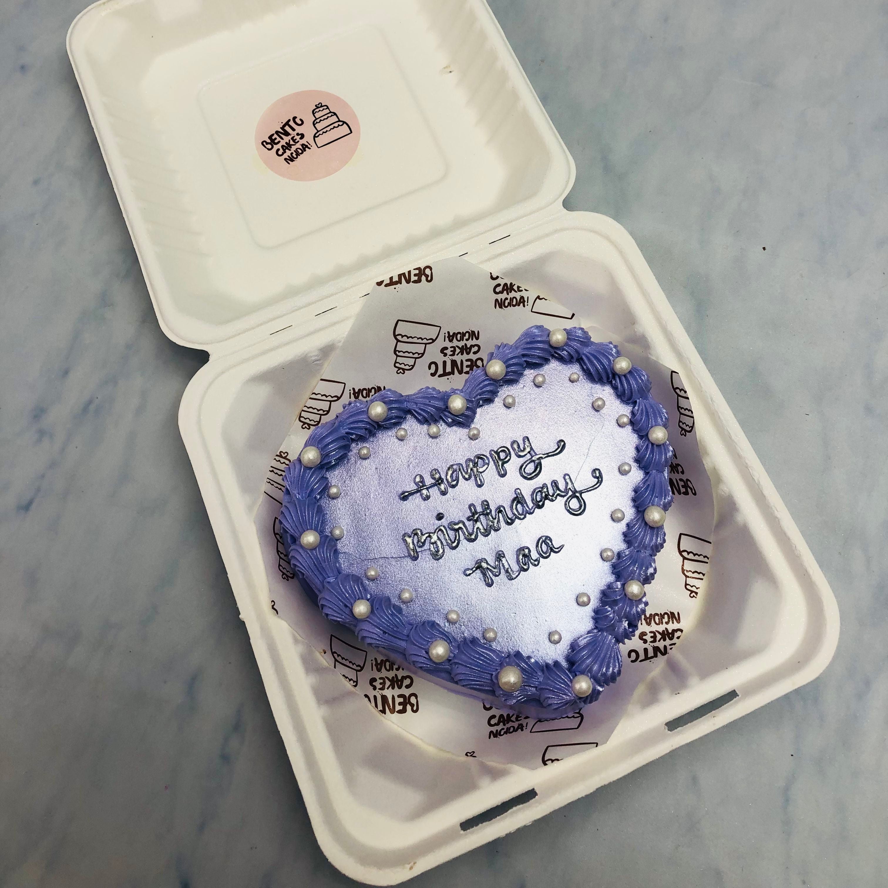 A shiney blue heart shape cake with glitters on top and decorated with white sprinkles.