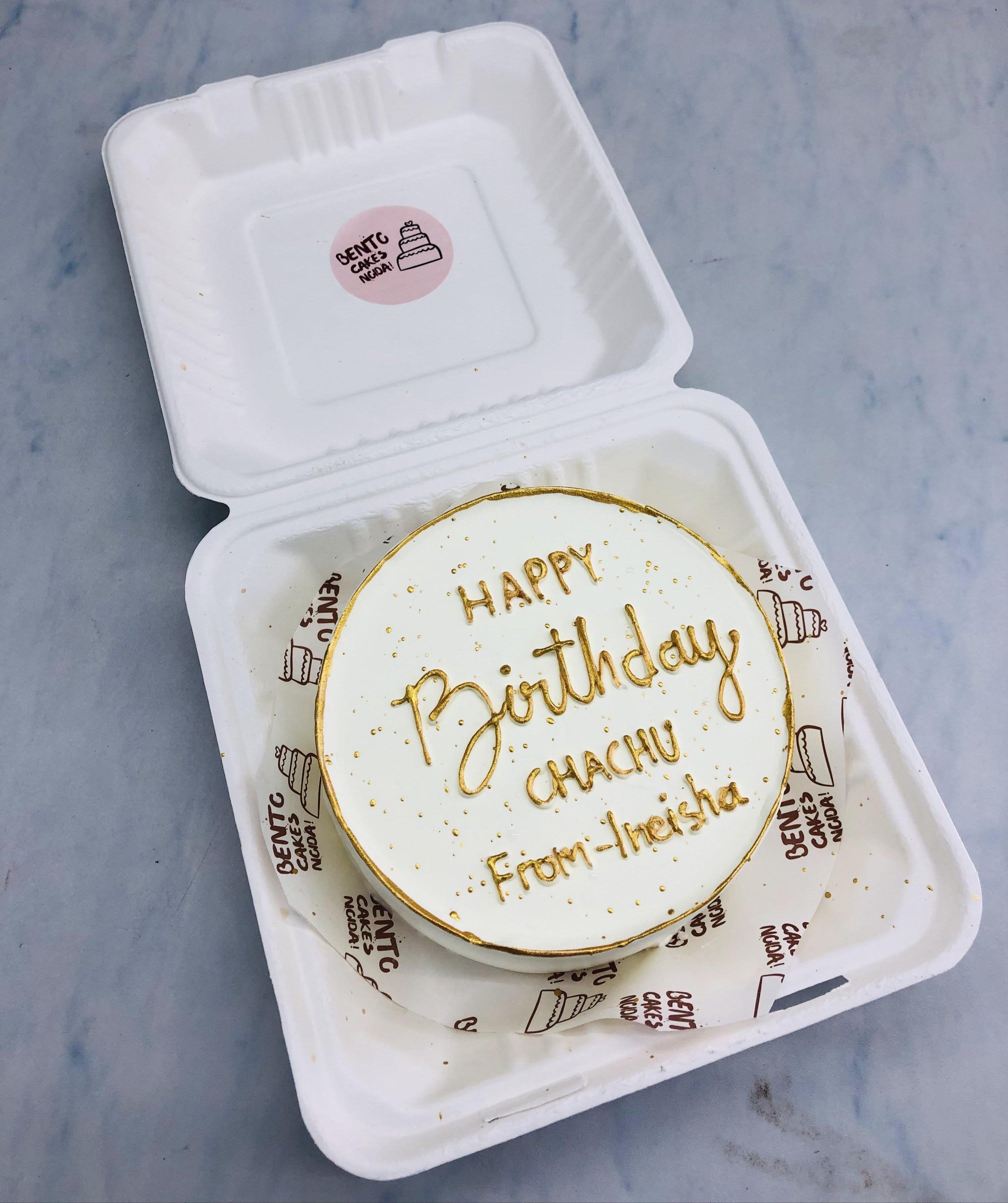 An aesthetic white bento cake with golden text for birthday.