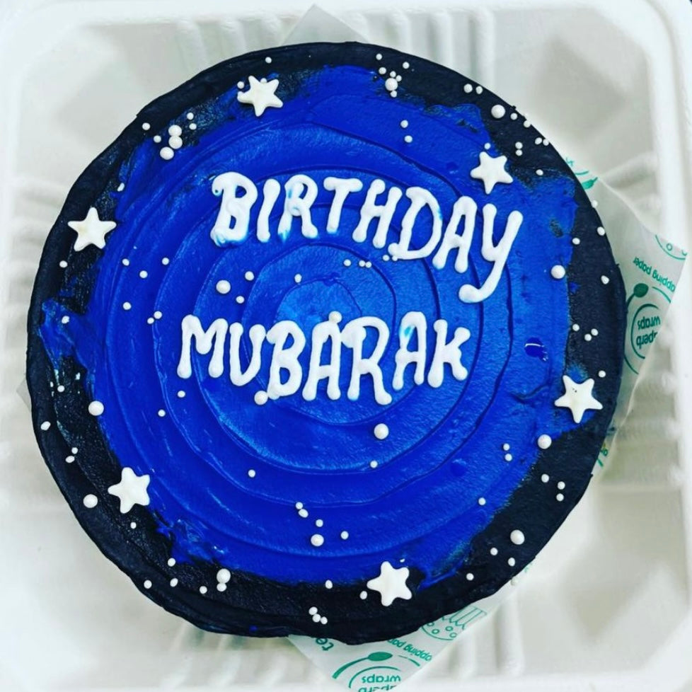 A colorful birthday cake featuring a space theme, adorned with decorations.