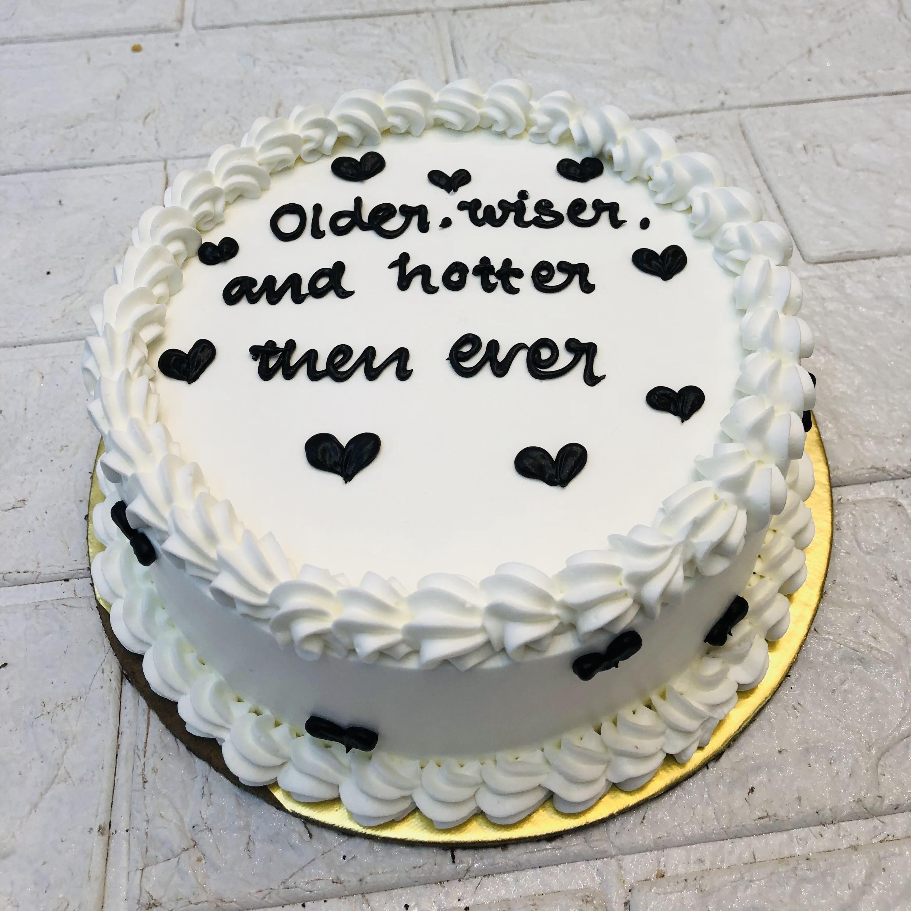 Pretty black hearts designed on white basic cake with "Older Wiser and Hotter Then Ever"