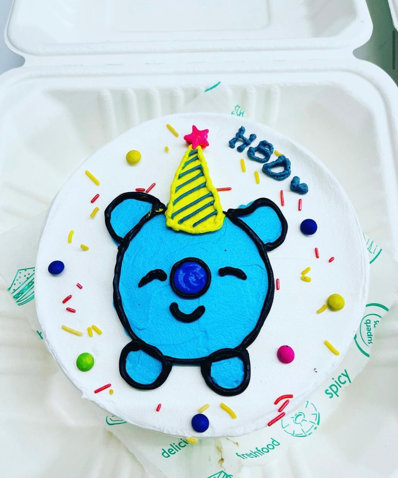 A cake decorated with a blue bear figure on top, showcasing a whimsical and playful design.