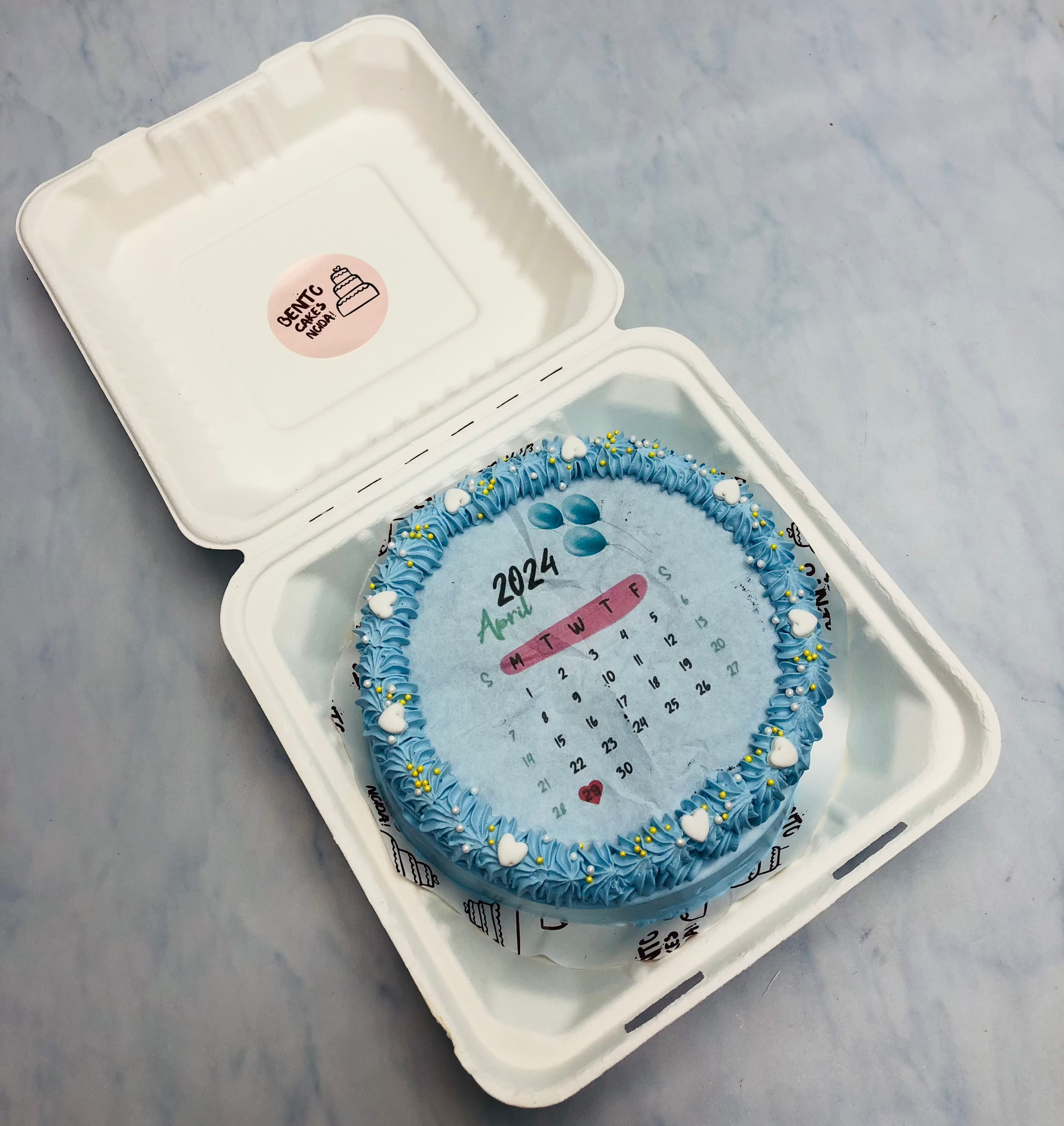 A pretty blue fire bento cake decorated with white hearts and august calendar printed on fire paper.