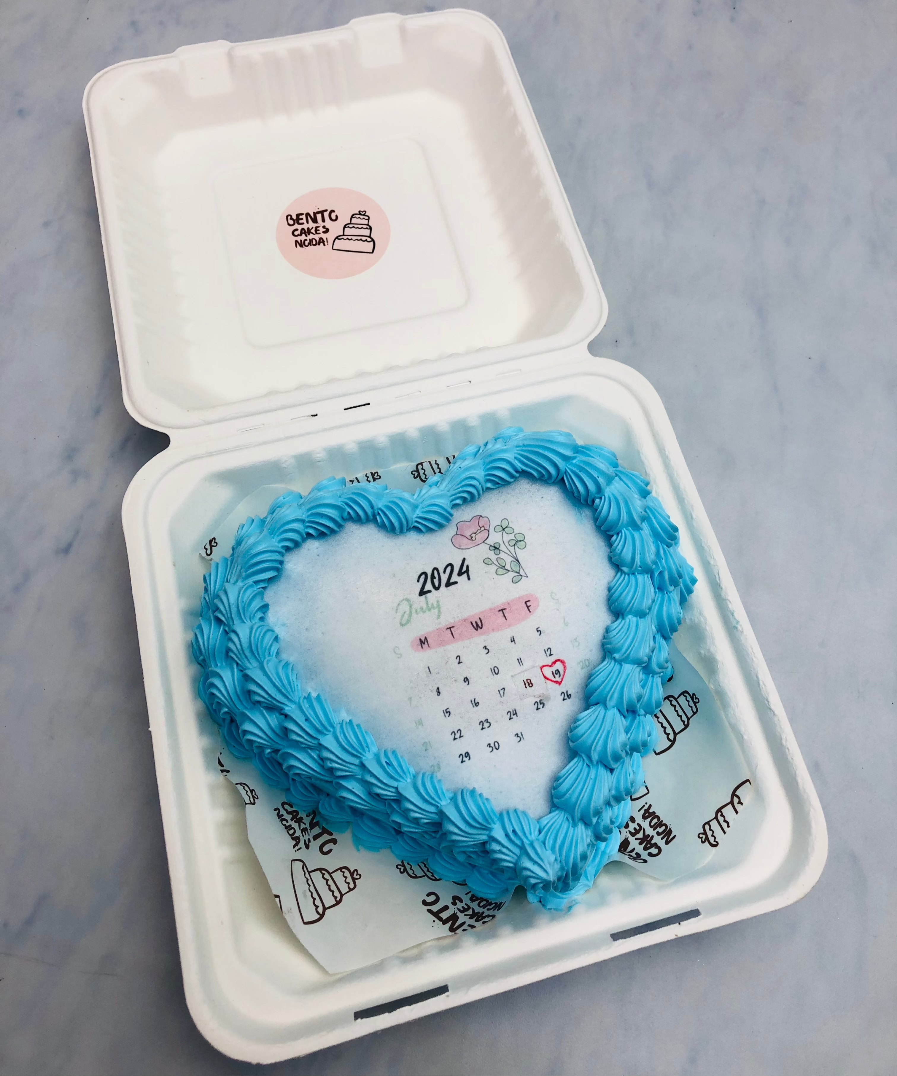 A sky blue truffle design on hearts shape fire bento cake with calendar theme.