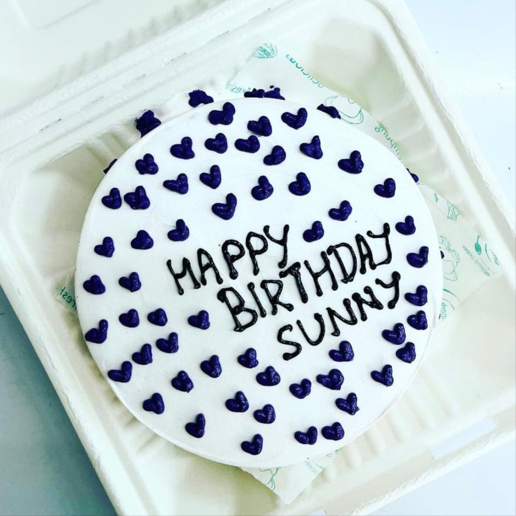 A delightful birthday cake encased in a soft foam container, showcasing the phrase "Happy Birthday Sunny" in bright letters.
