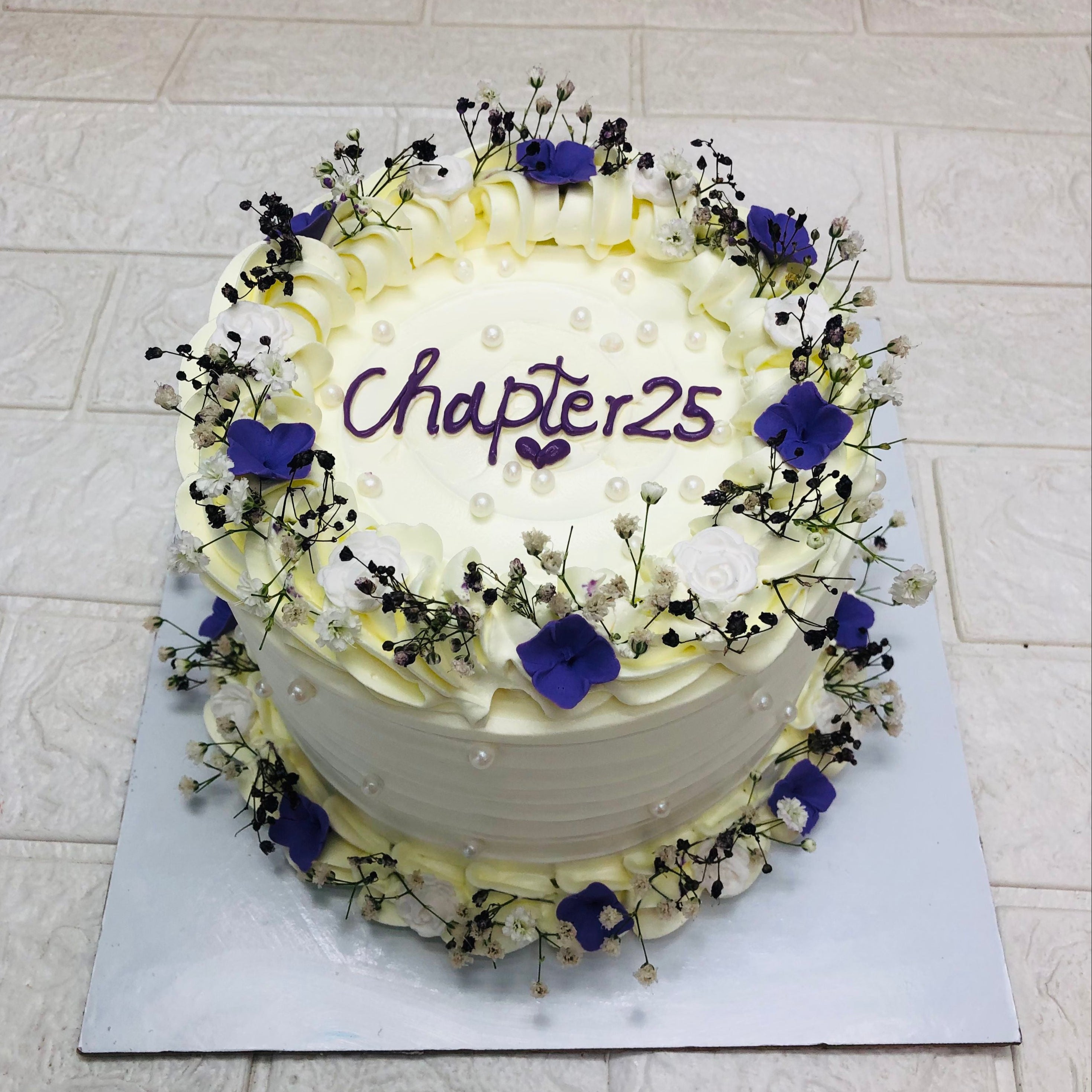 A white cake adorned with delicate blue and purple flowers, elegantly arranged for a festive occasion.