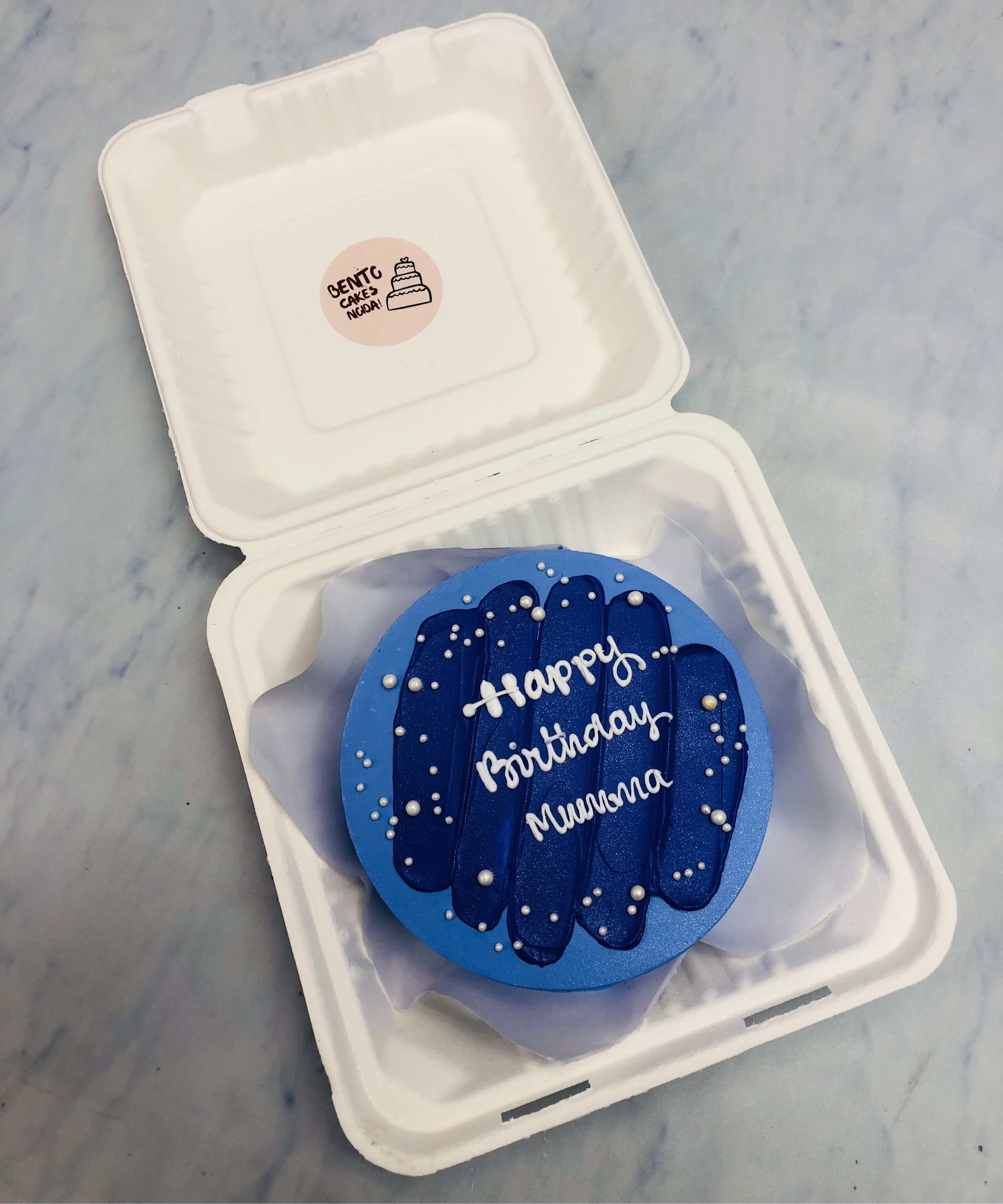 A dark blue shades design on blue bento cake with a "Happy Birthday Mumma" text written with white icing.