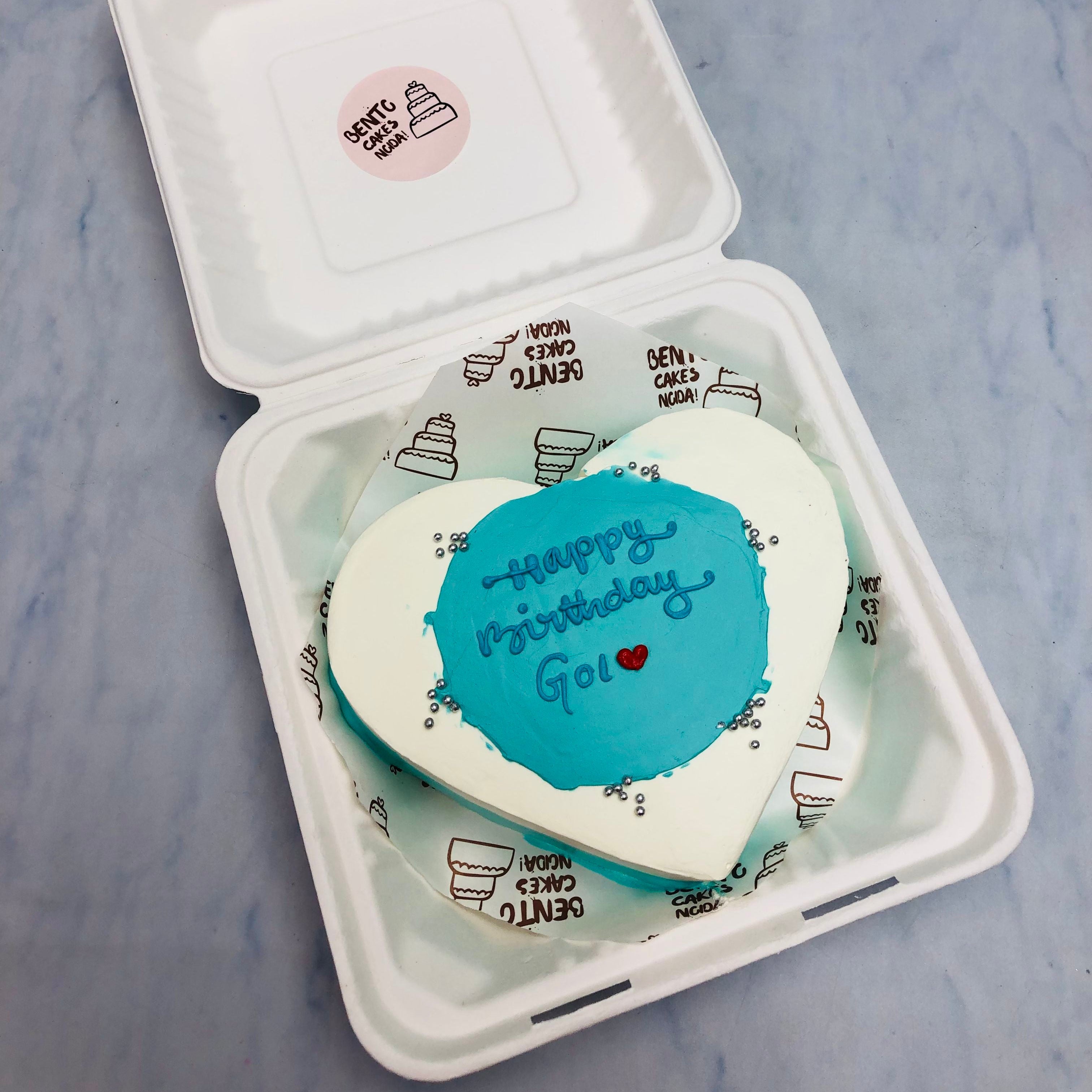 A white blue heart shape cake with blue shades in center and decorated with some silver sprinkles.