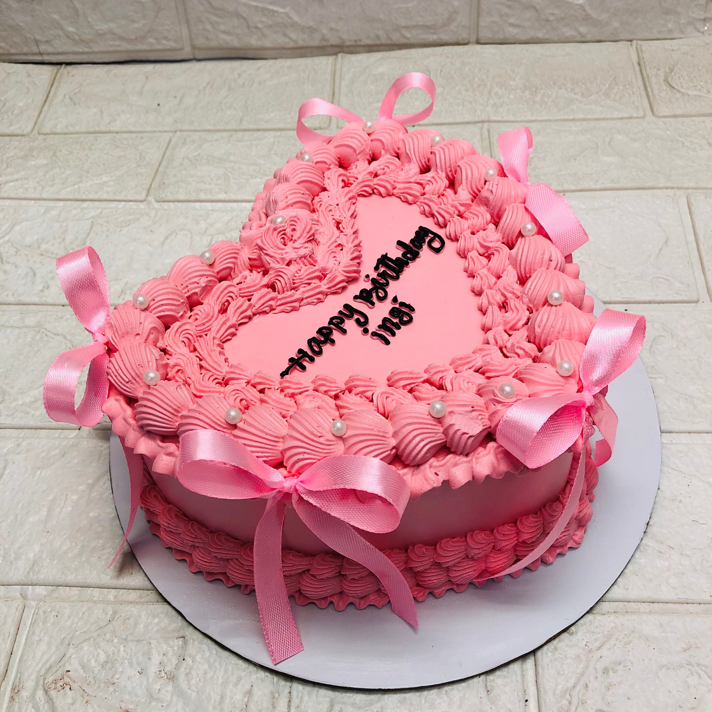 A beautifully crafted pink heart-shaped cake featuring an elegant ribbon bow, ideal for romantic celebrations.