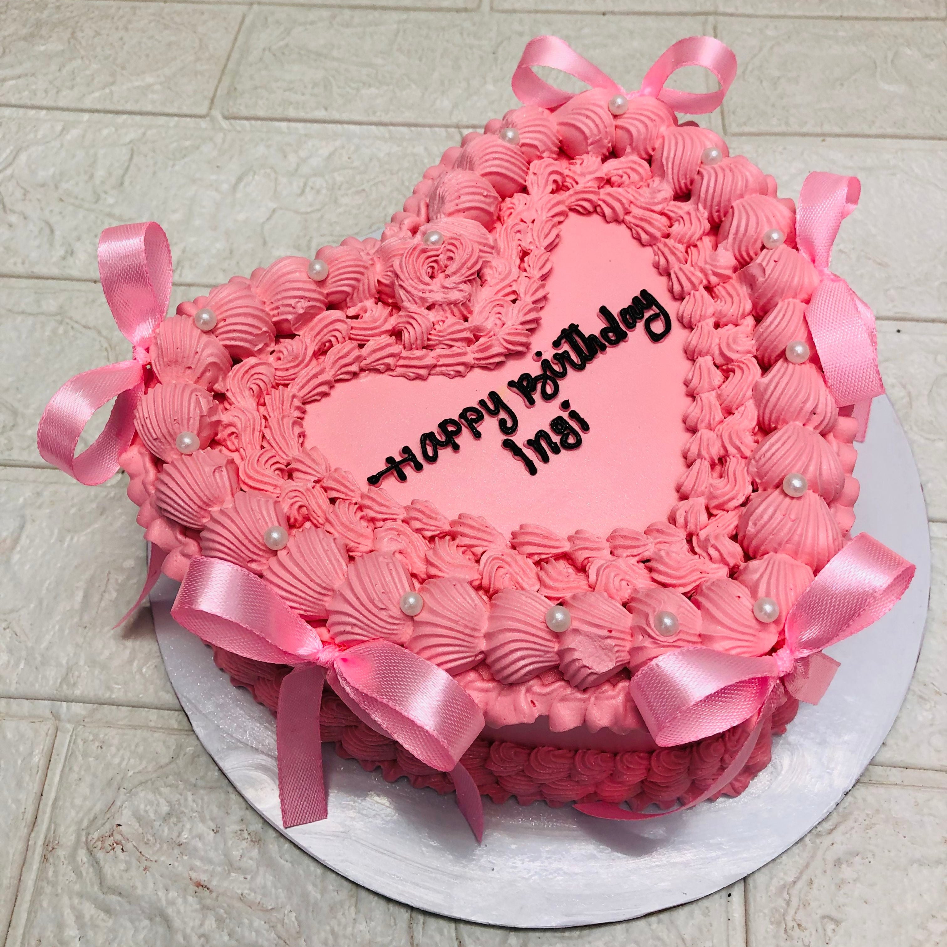 A beautifully crafted pink heart-shaped cake featuring an elegant ribbon bow, ideal for romantic celebrations.